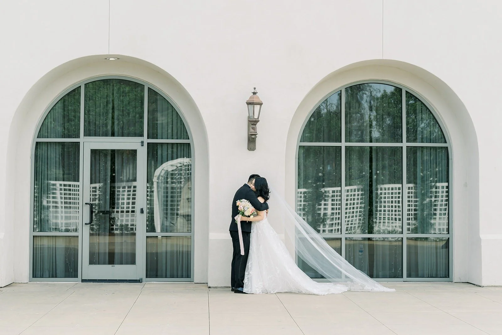 Francesca and Ralph in front of arched windows in a white courtyard