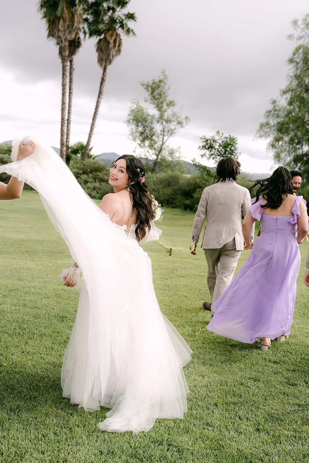 Kat swishing her gown on the lawn with the wedding party