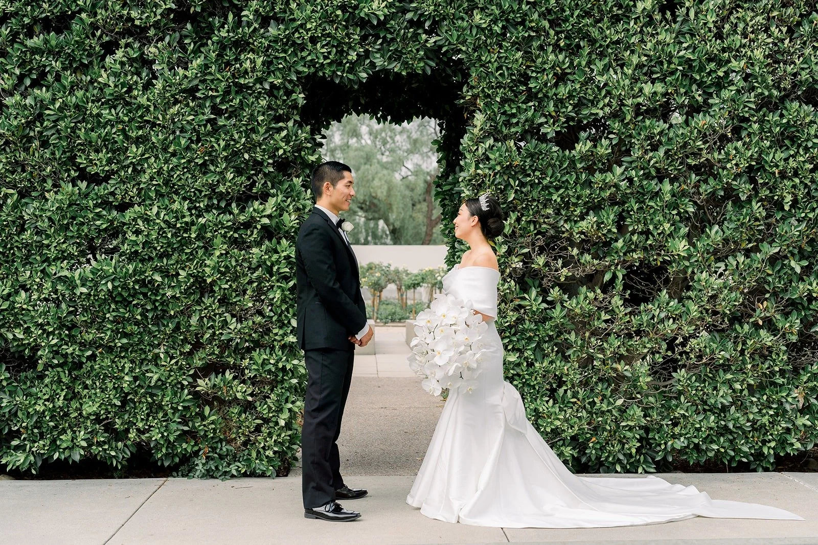 Steven and Jacinda in front of a tall green hedge