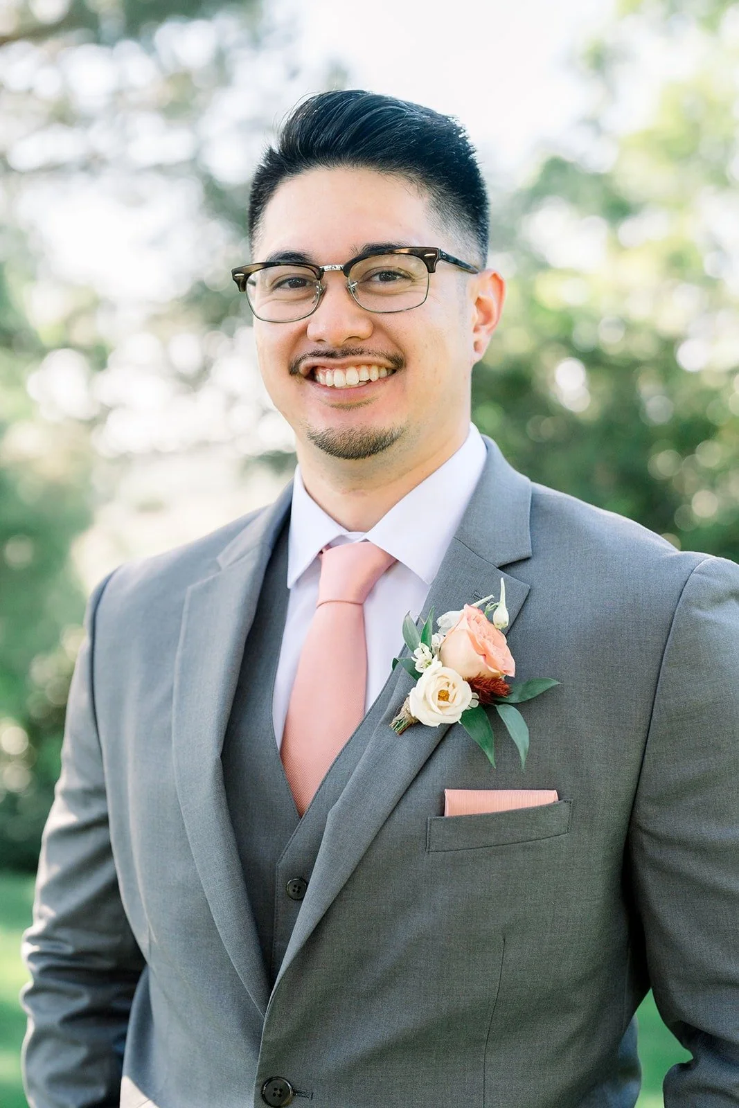 Mikey smiles in his grey suit and glasses