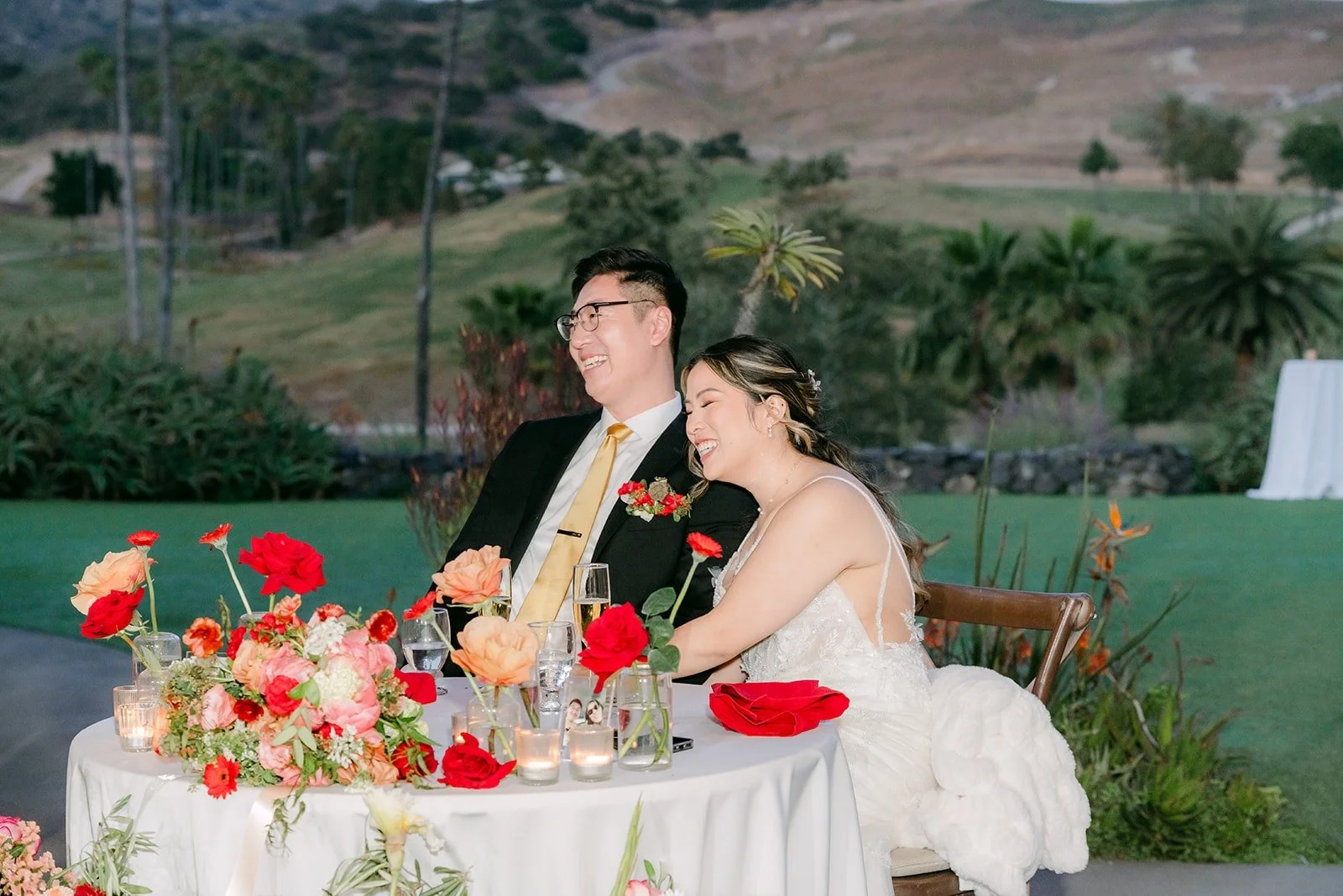 Zach and Joanne leaning together at the sweetheart table during a toast