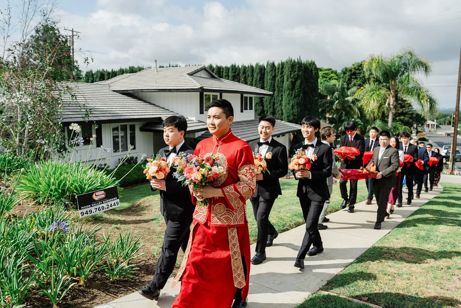 The groom's procession walking up the street with red gift trays.