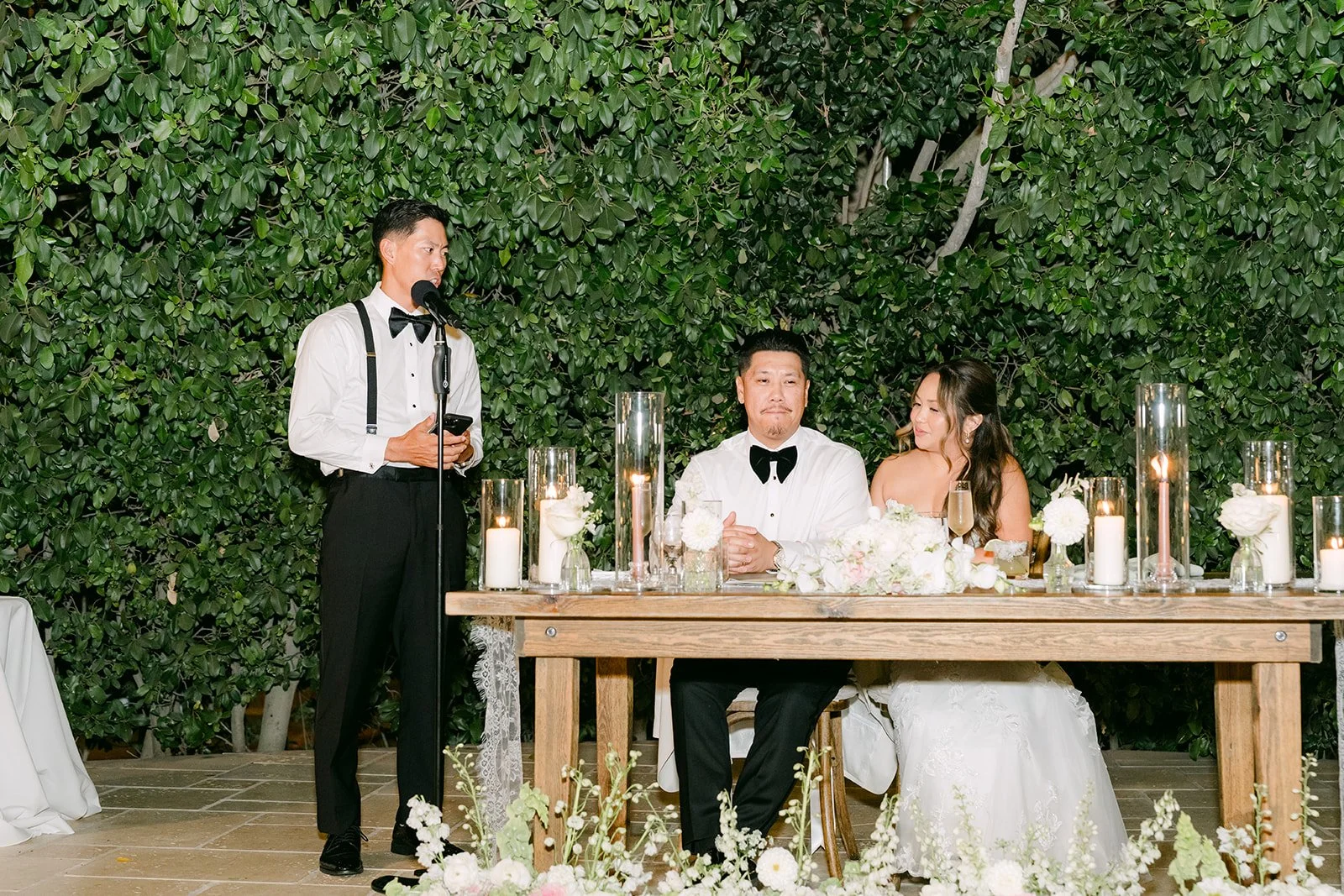 A best man giving his toast beside Nicole and Caryl's sweetheart table.