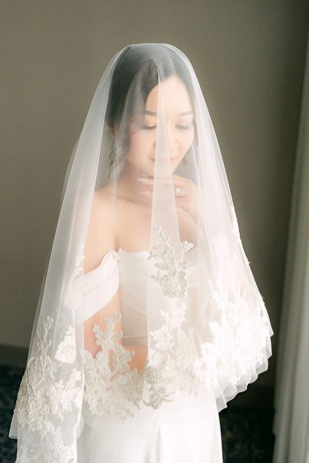 Amanda under her veil by a bright window.