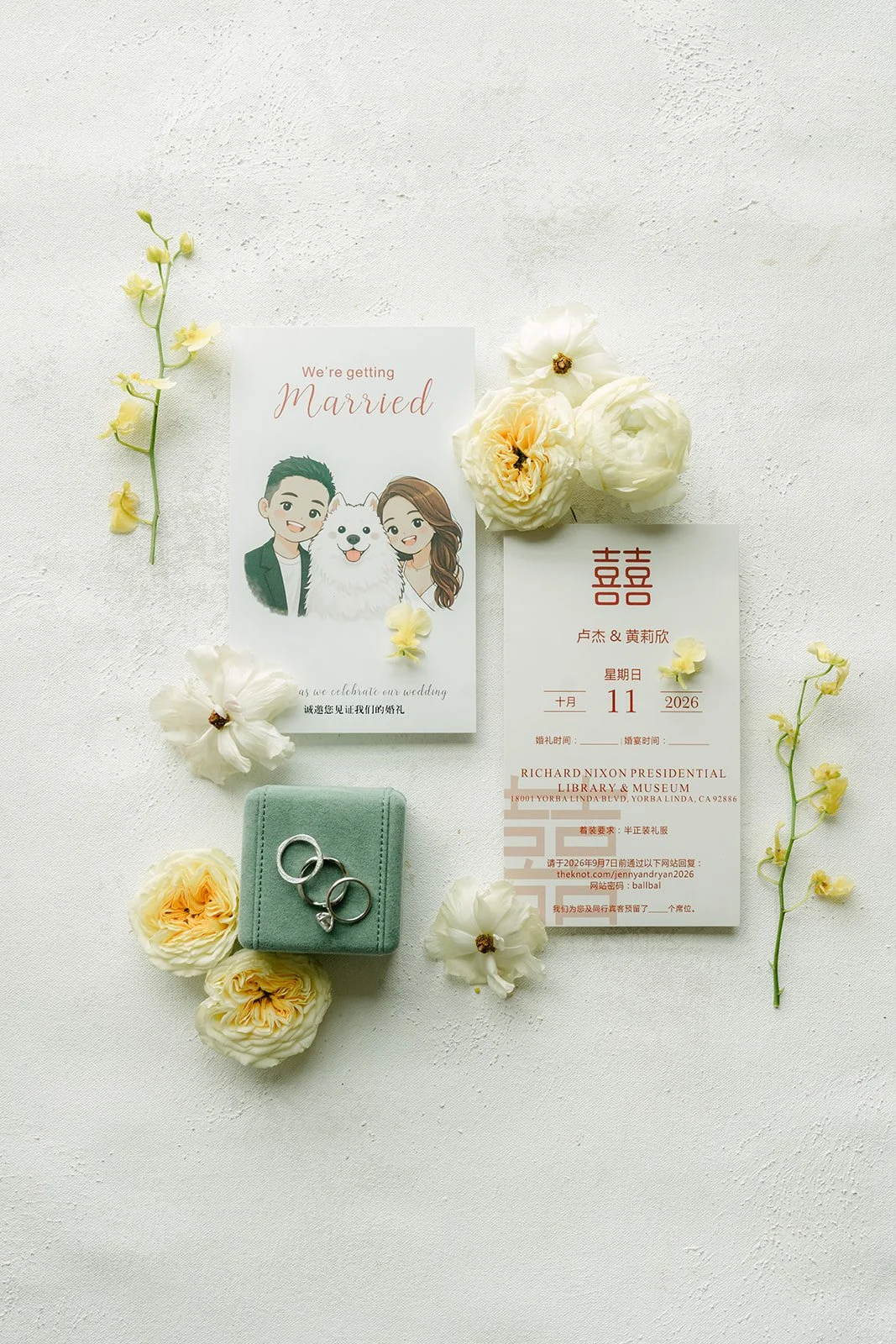 Invitation suite with a green ring box and butter yellow roses for Jenny and Ryan's flat lay.