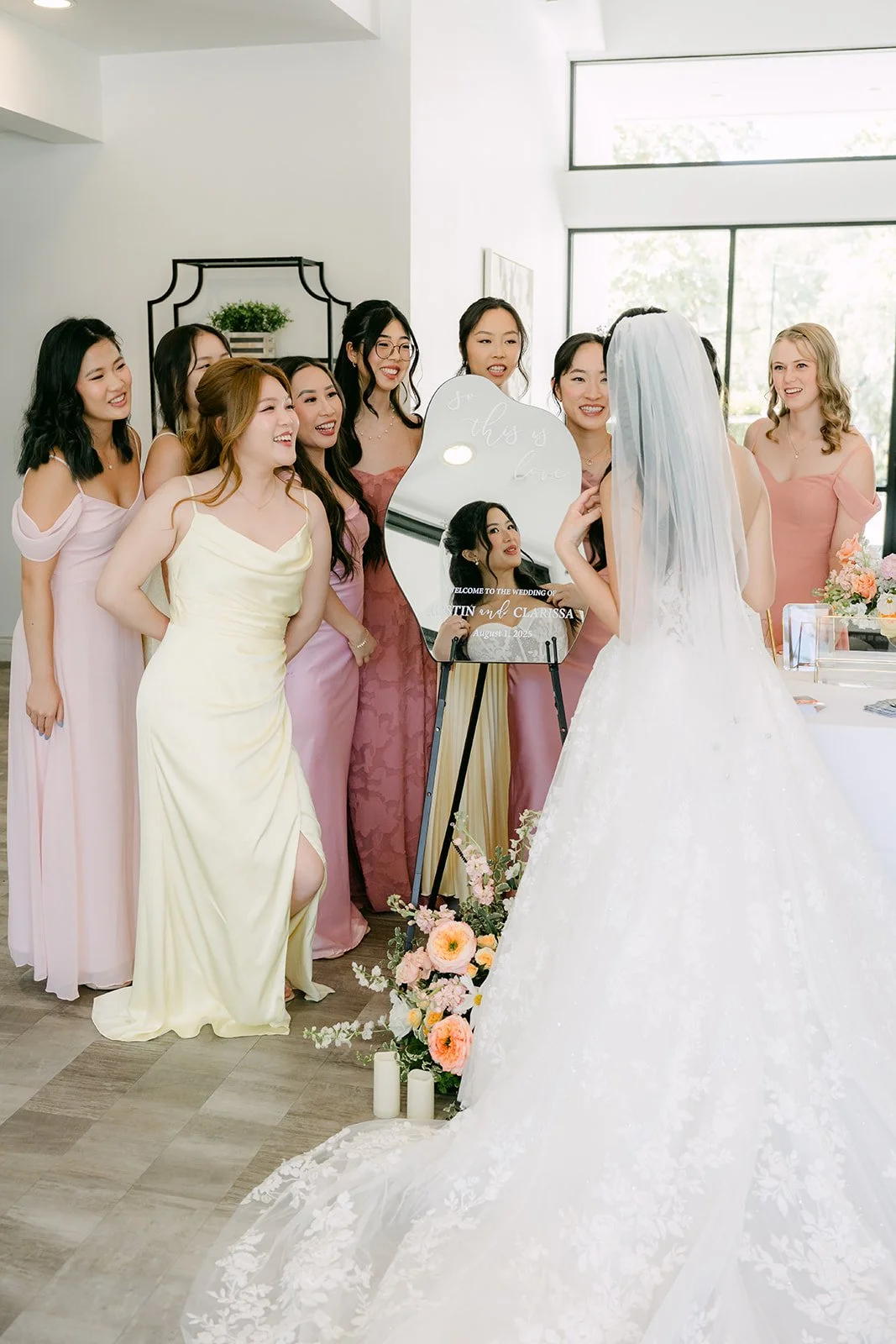 Bridesmaids in mixed pastel gowns gathered around Clarissa