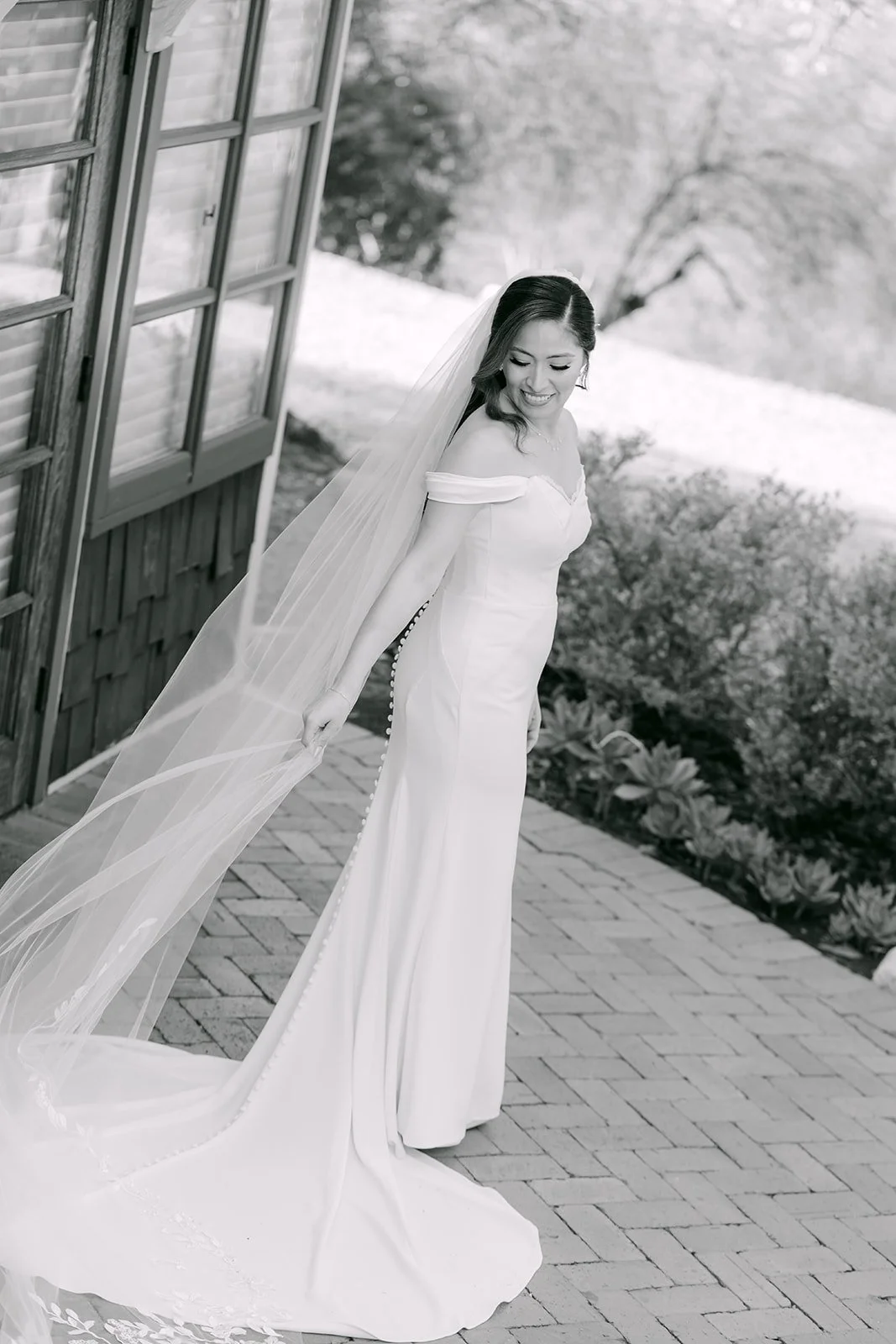 Black and white portrait of Mariana with her veil lifted in the breeze