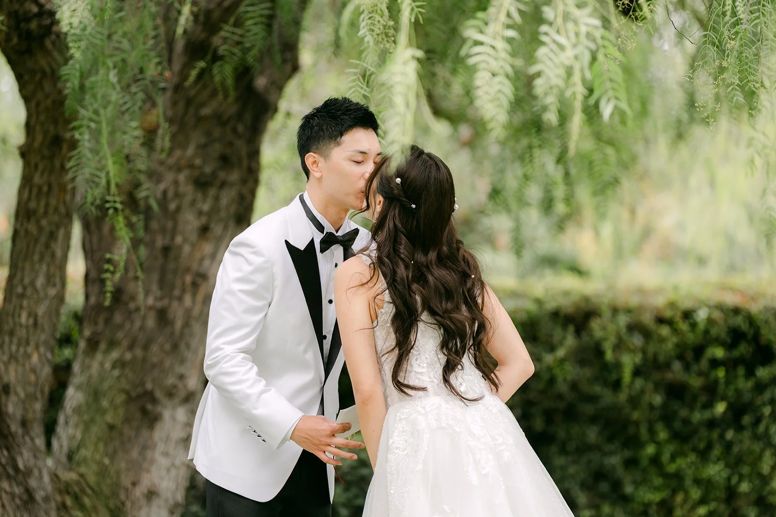 Jenny and Ryan kissing beside a weeping tree after their vows.