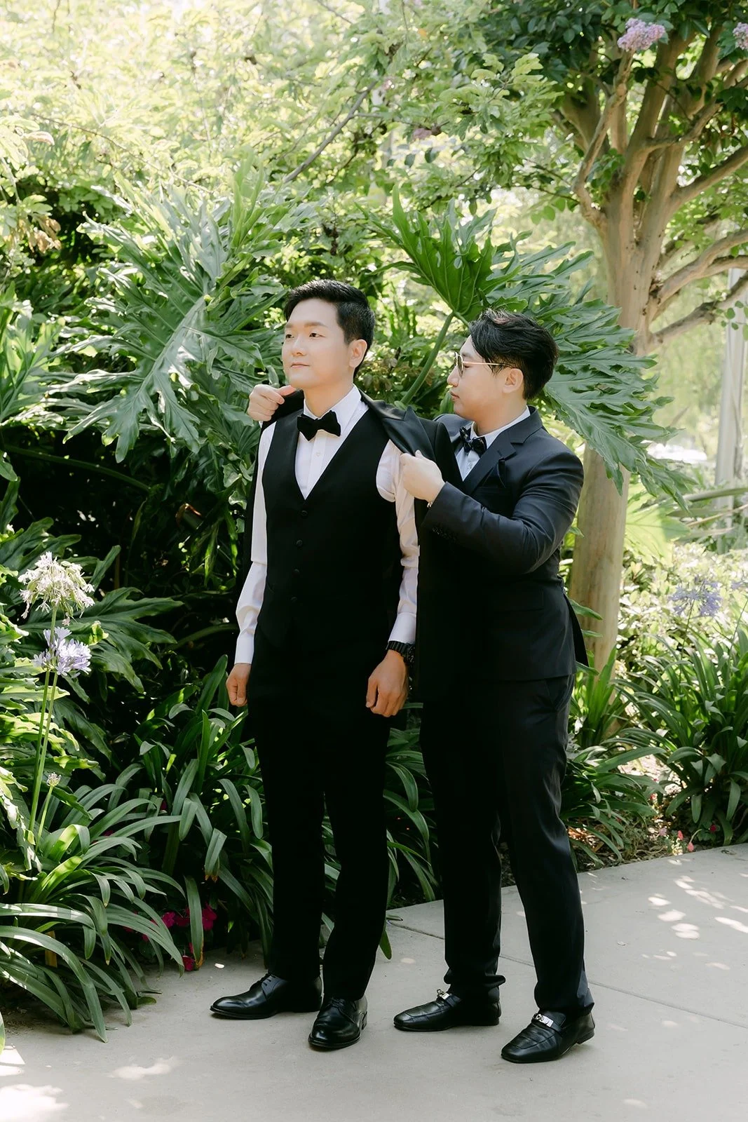 Eunsang getting help with his tuxedo jacket among the tropical plants