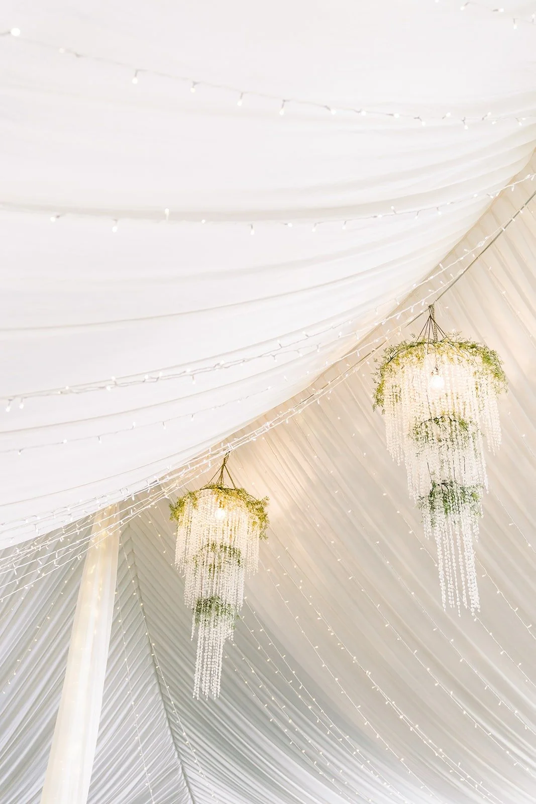 Crystal chandeliers hanging inside the draped reception tent