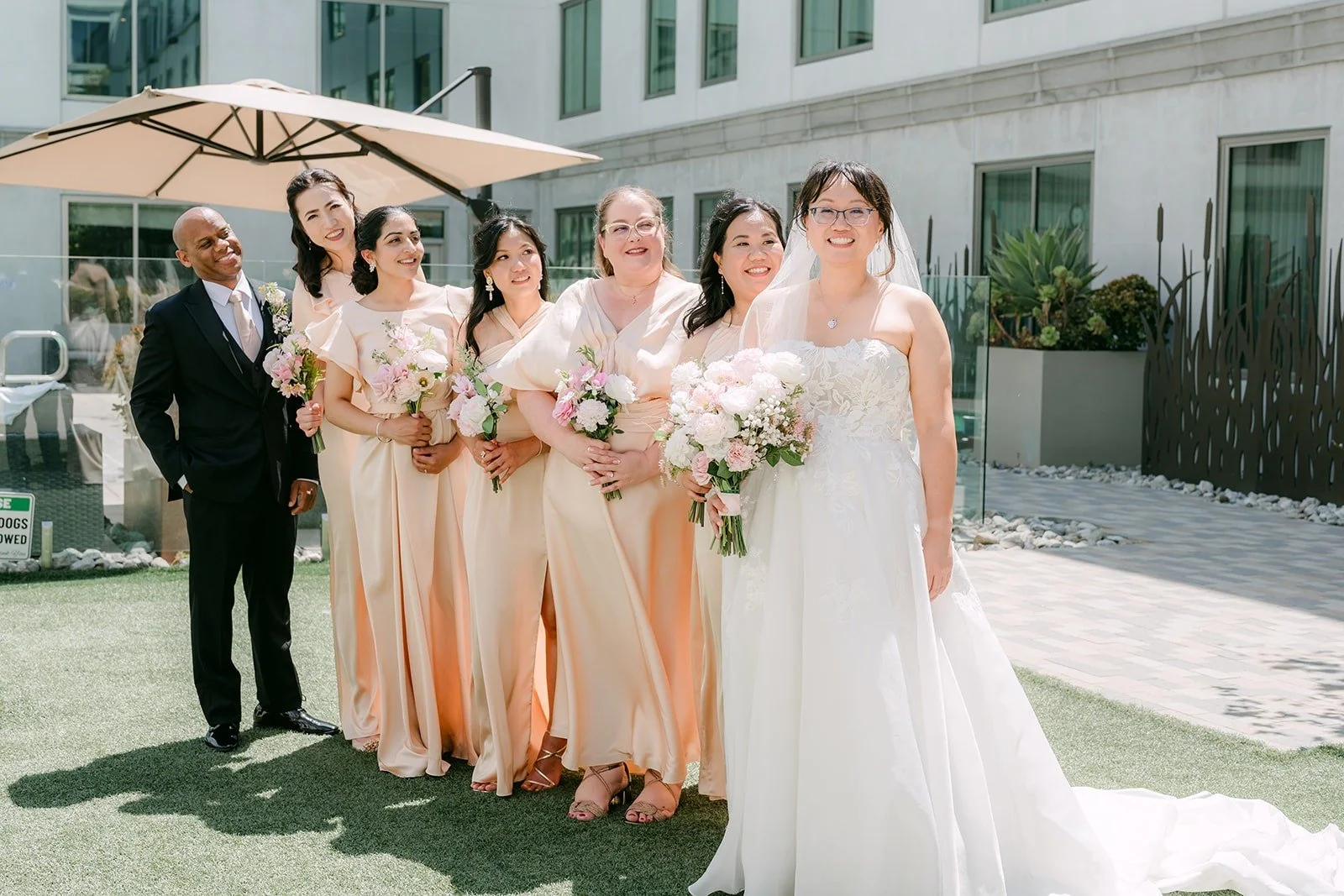 Stella and her bridesmaids and bridesman gathered on the lawn under the hotel windows, photographed by One and Only Production