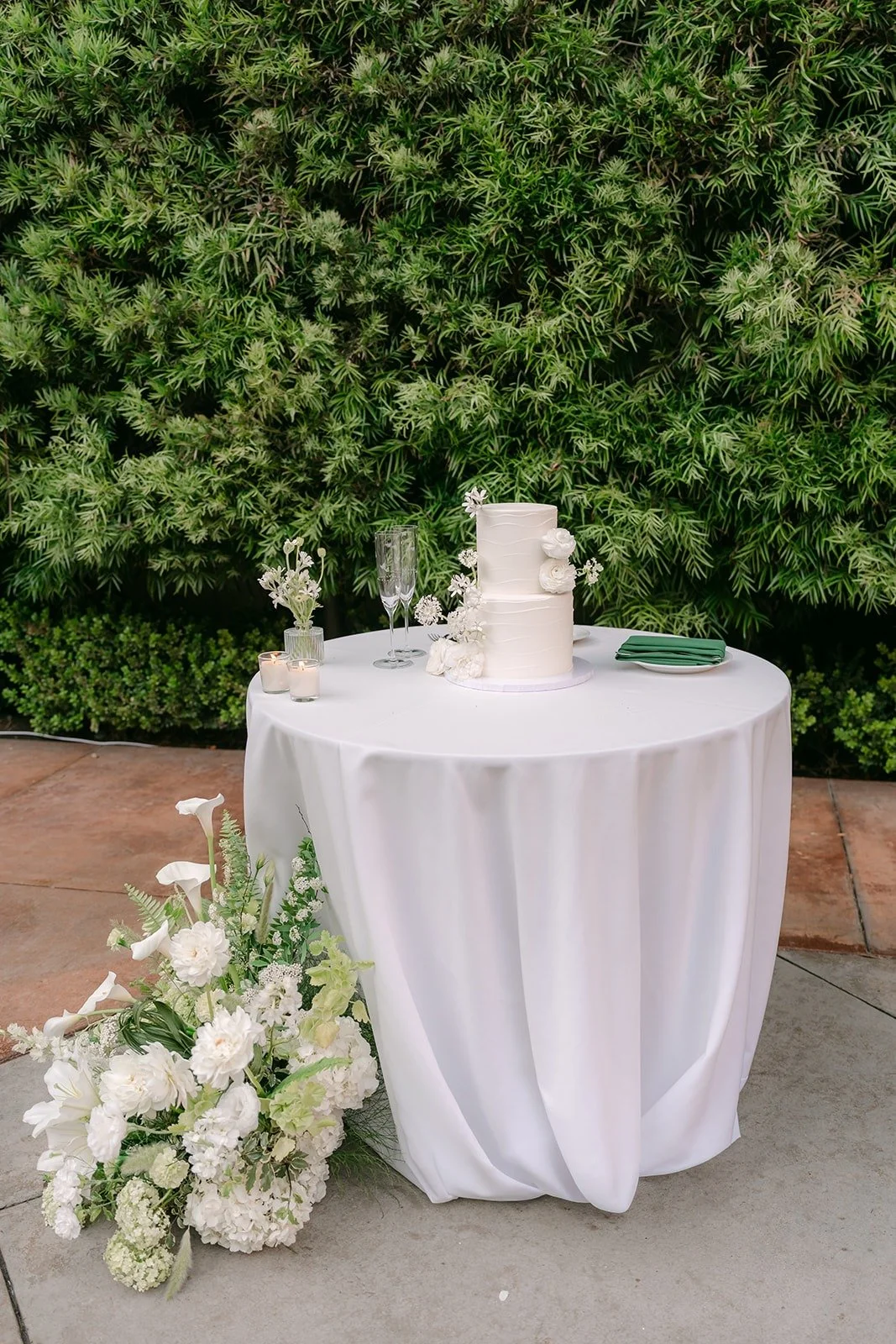 Chorok and Min Soo's white wedding cake on a table against the hedges