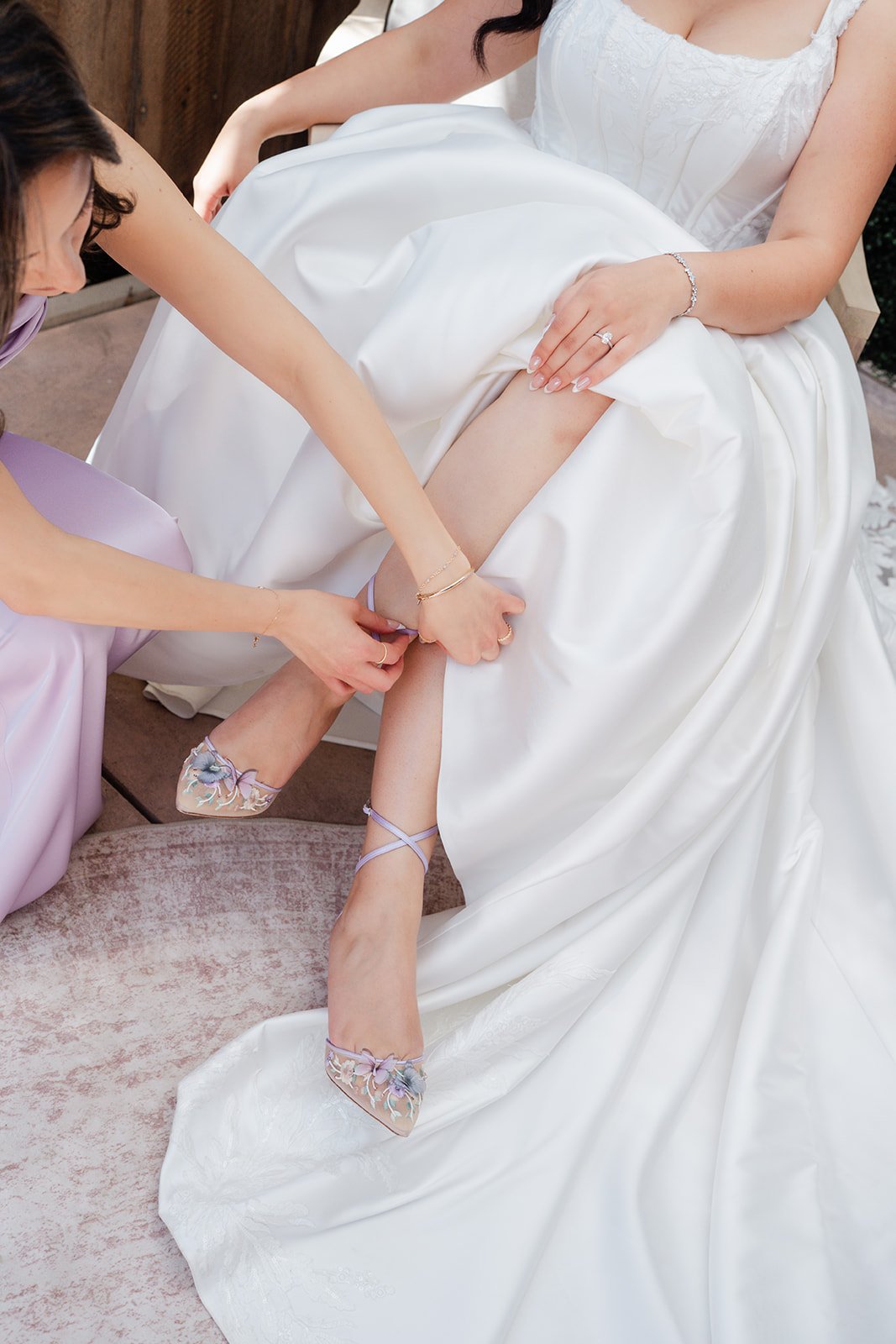 Bridesmaid fastening the bride's jeweled shoe