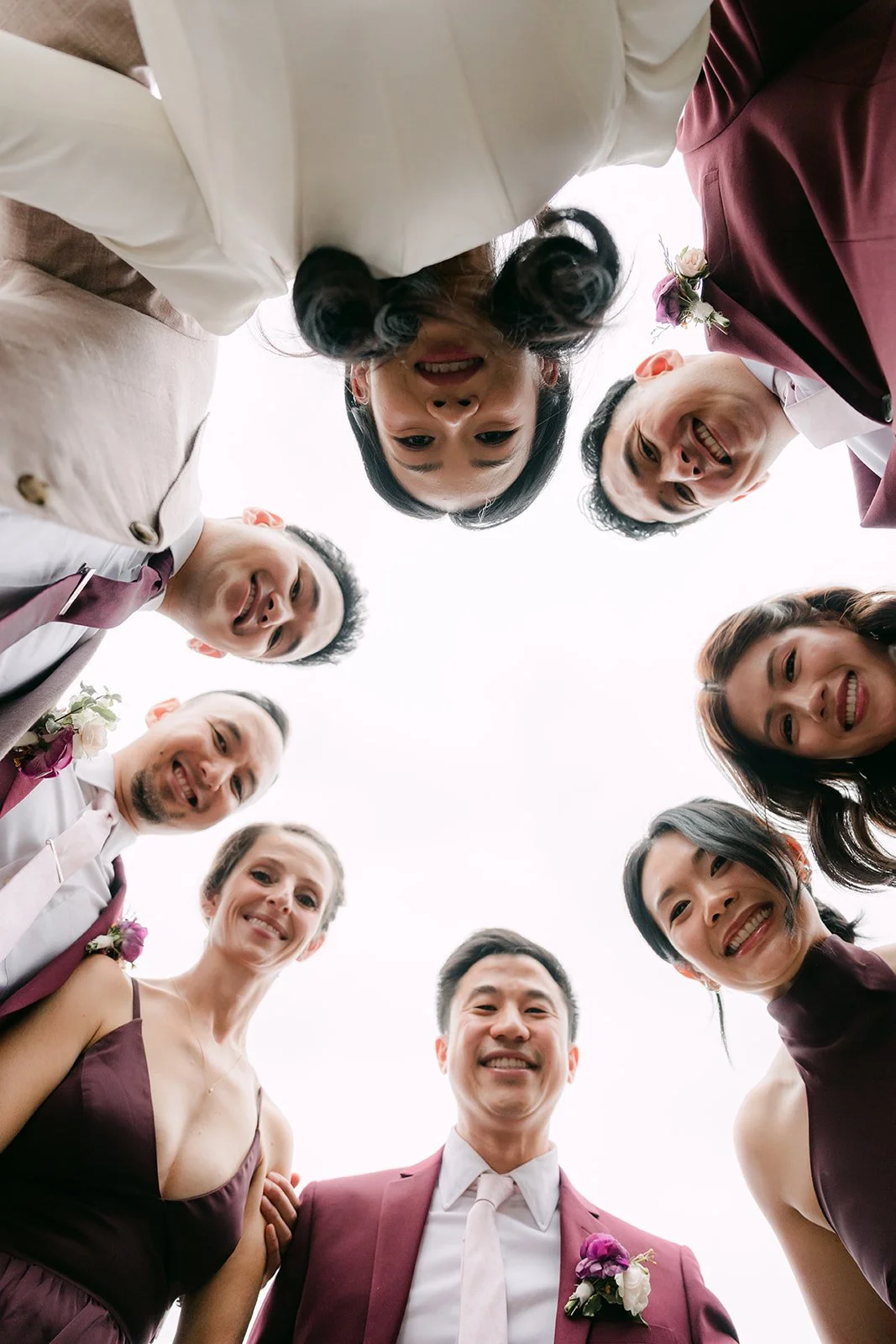 The wedding party looking down into the camera in a circle.