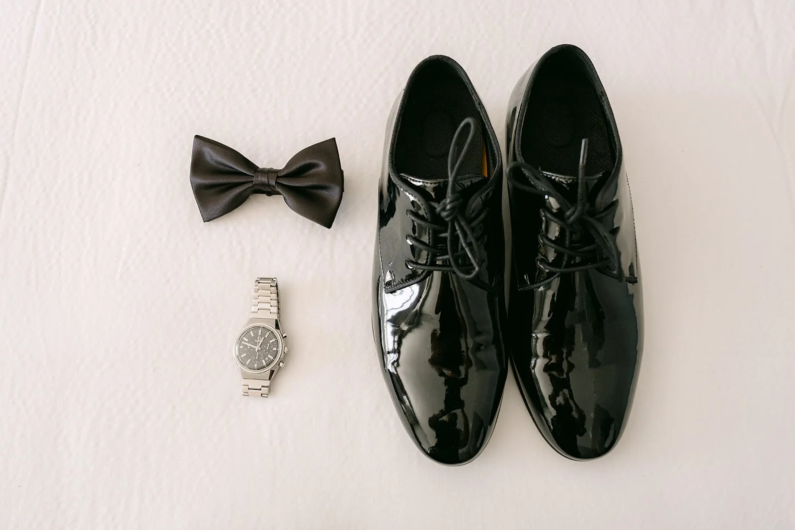 San's bow tie, watch and patent leather shoes laid out for the wedding.