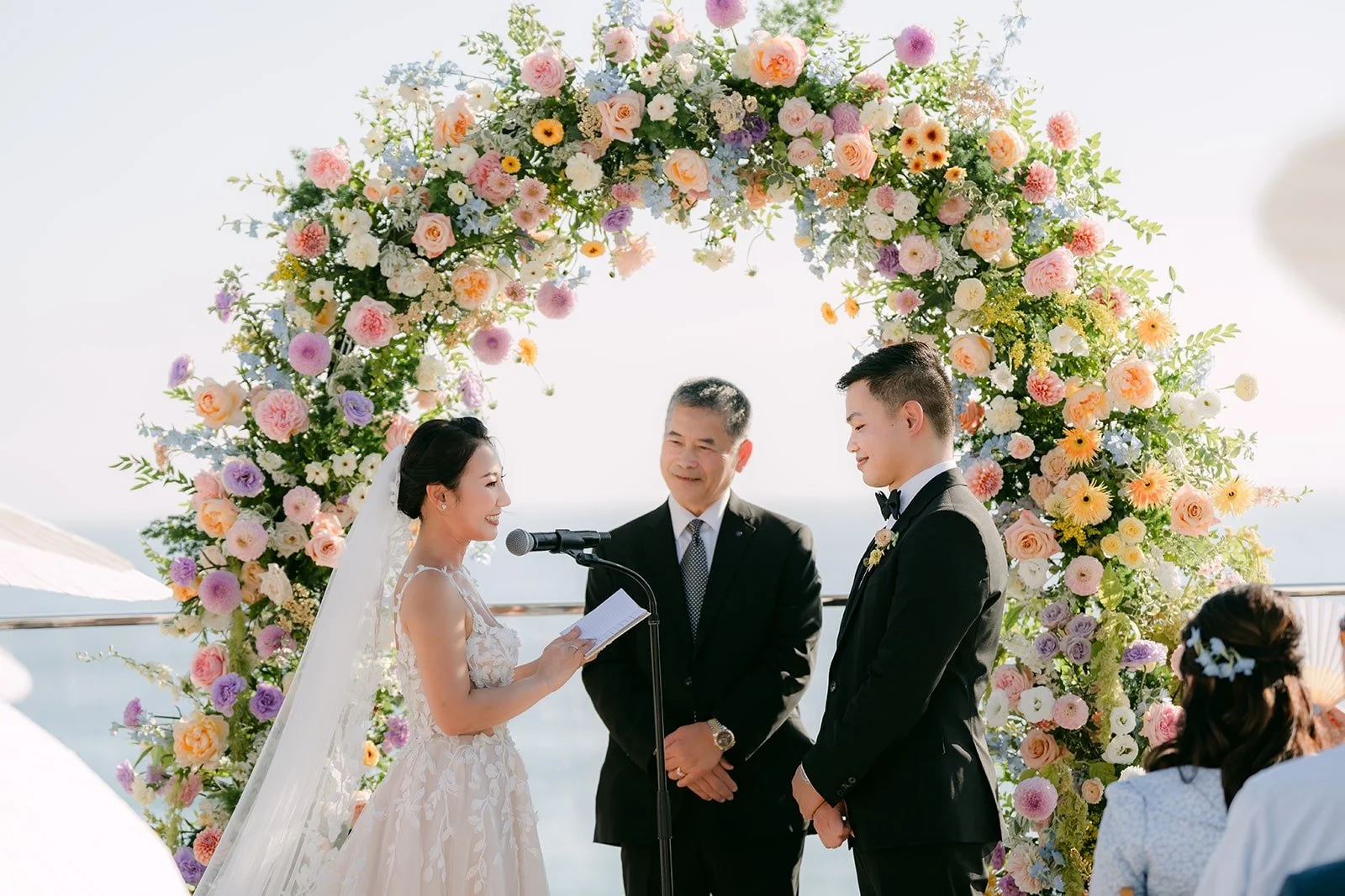 Kylie reading her vows under the floral arch