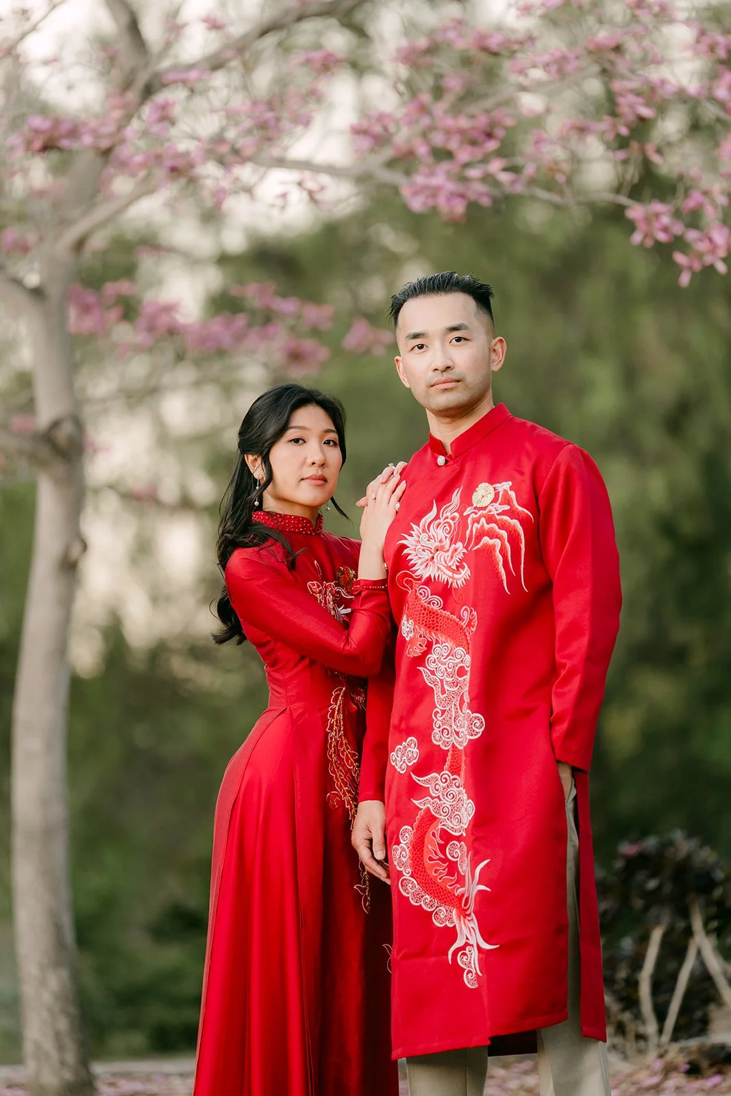 Kim and Vincent showing the embroidered details of their ao dai beneath the blossoms.