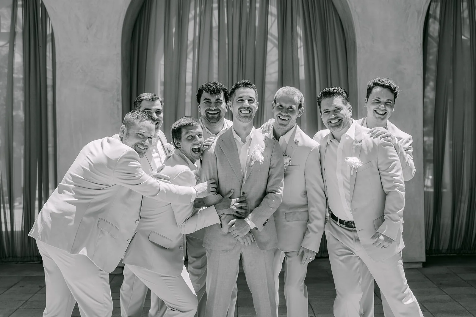 Black and white photo of the groomsmen goofing around in linen suits