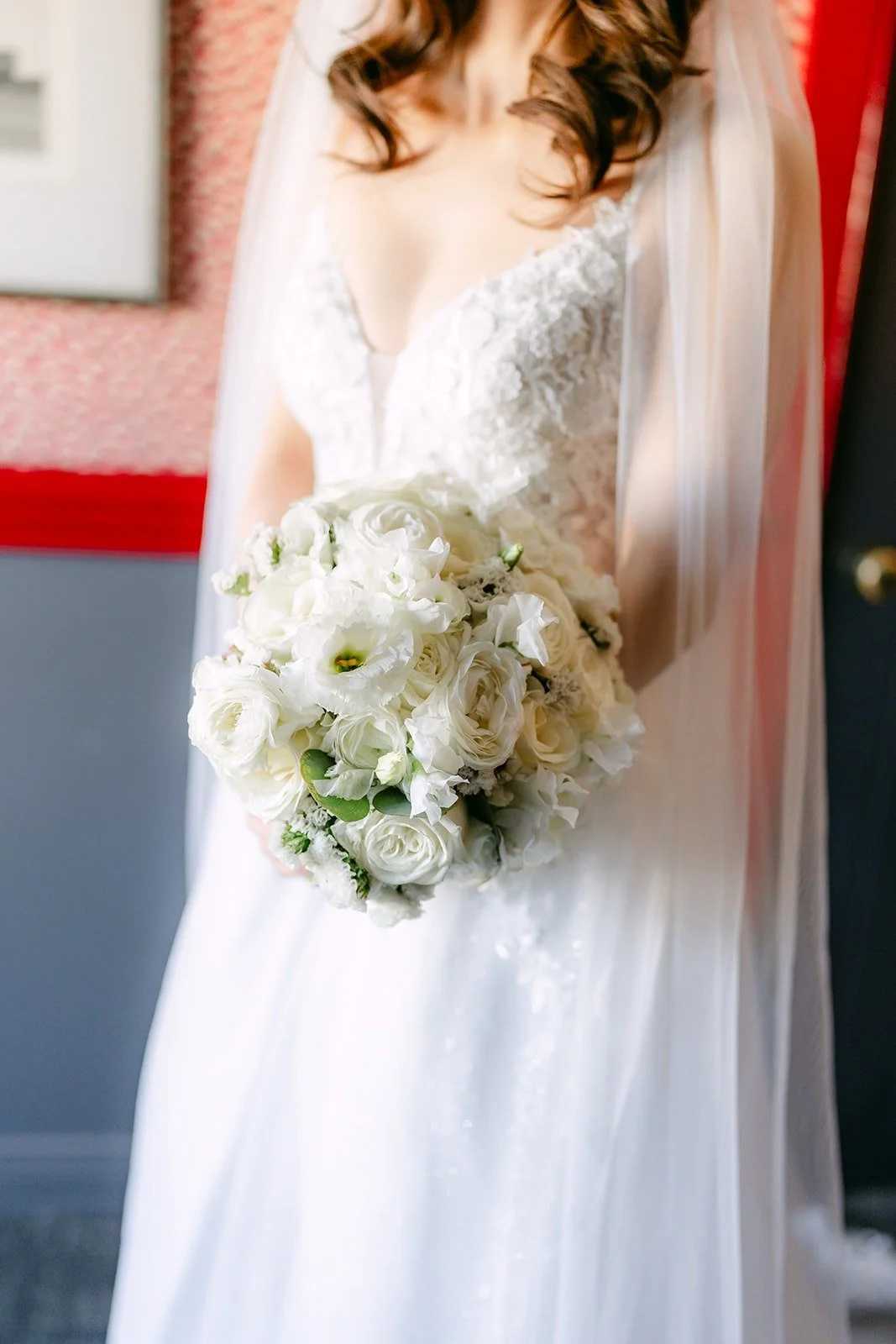 Valerie holding her white bouquet in her lace wedding gown