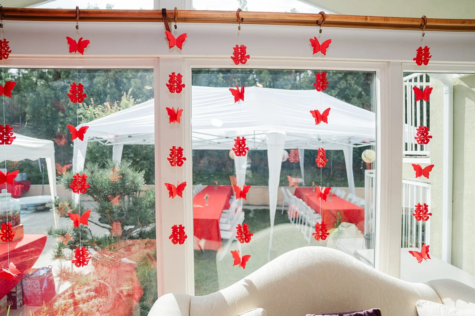 Red double happiness papercuts hanging in the windows overlooking the backyard, photographed by One and Only Production.