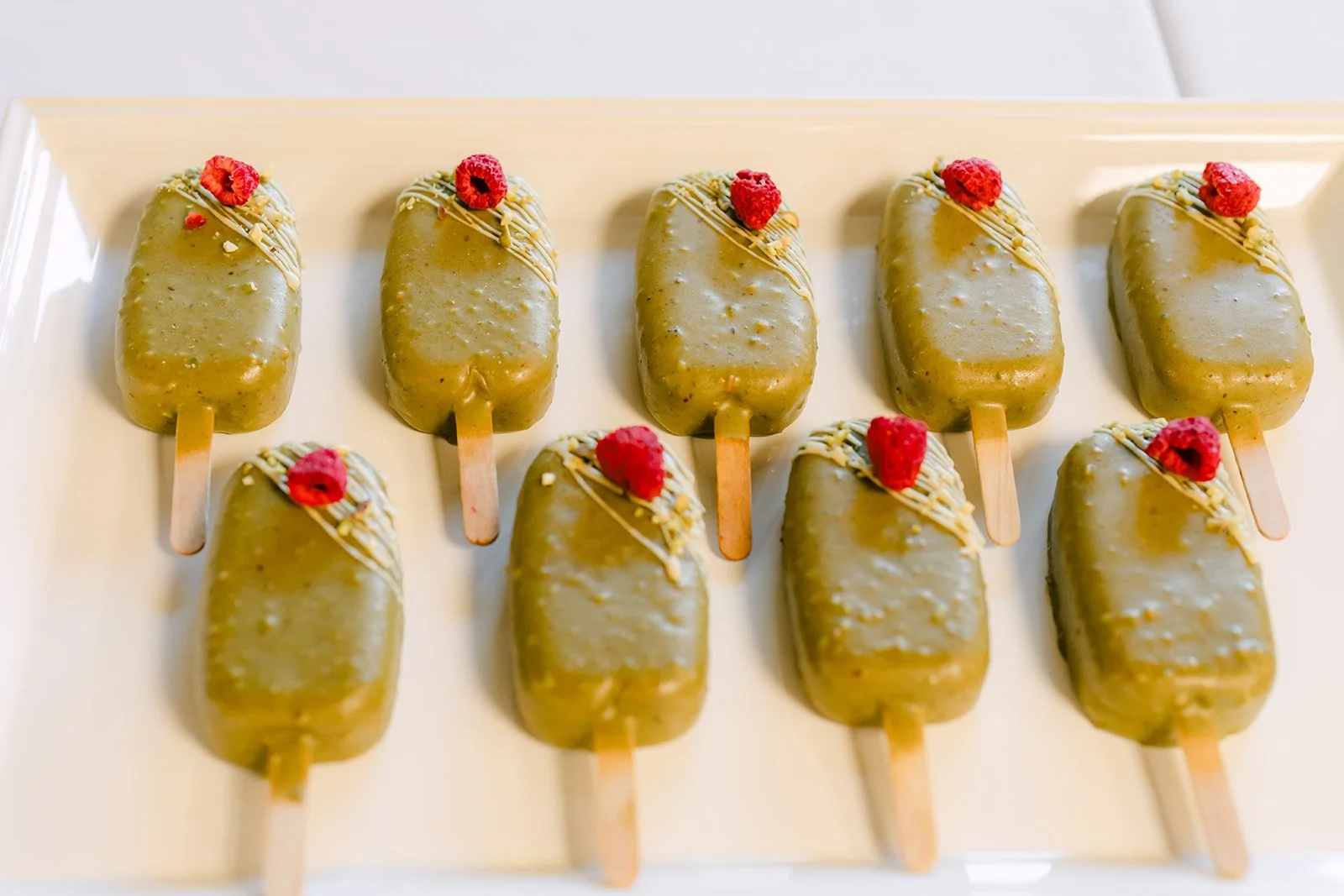 Pistachio-dipped dessert pops lined up on the dessert table.
