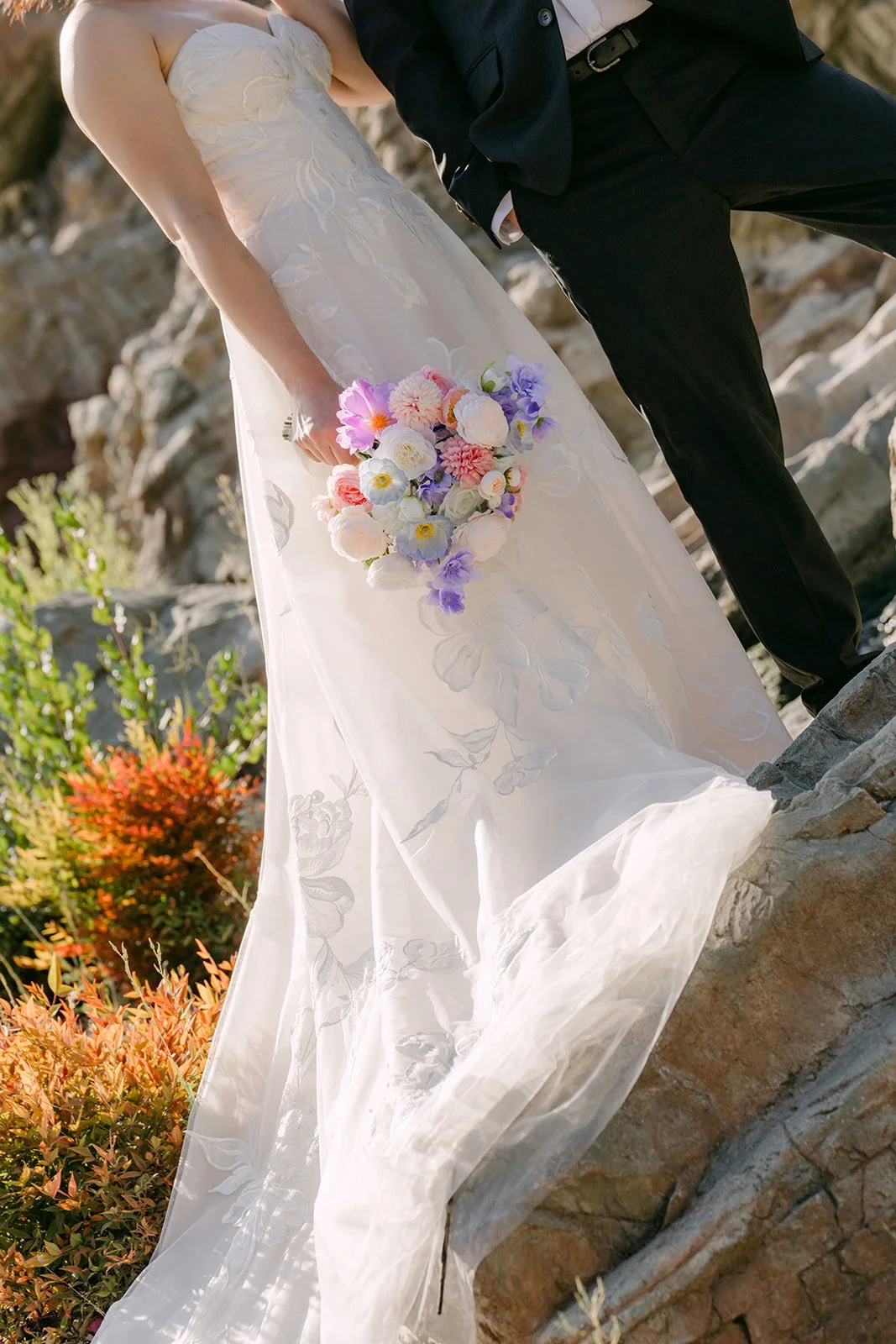 Mary's bouquet and lace gown on the rocks