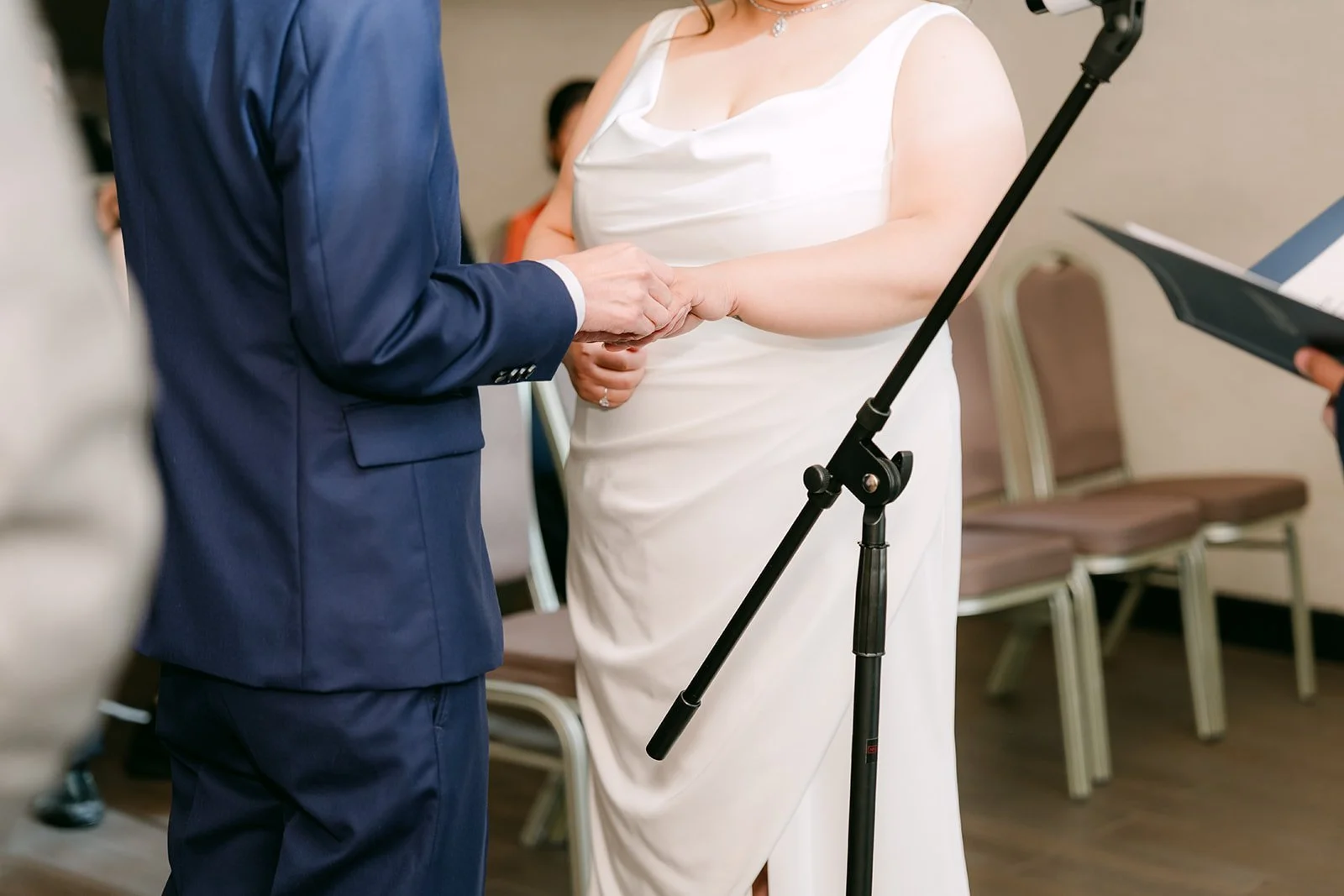 Close-up of Mai and Bobby holding hands during their vows.