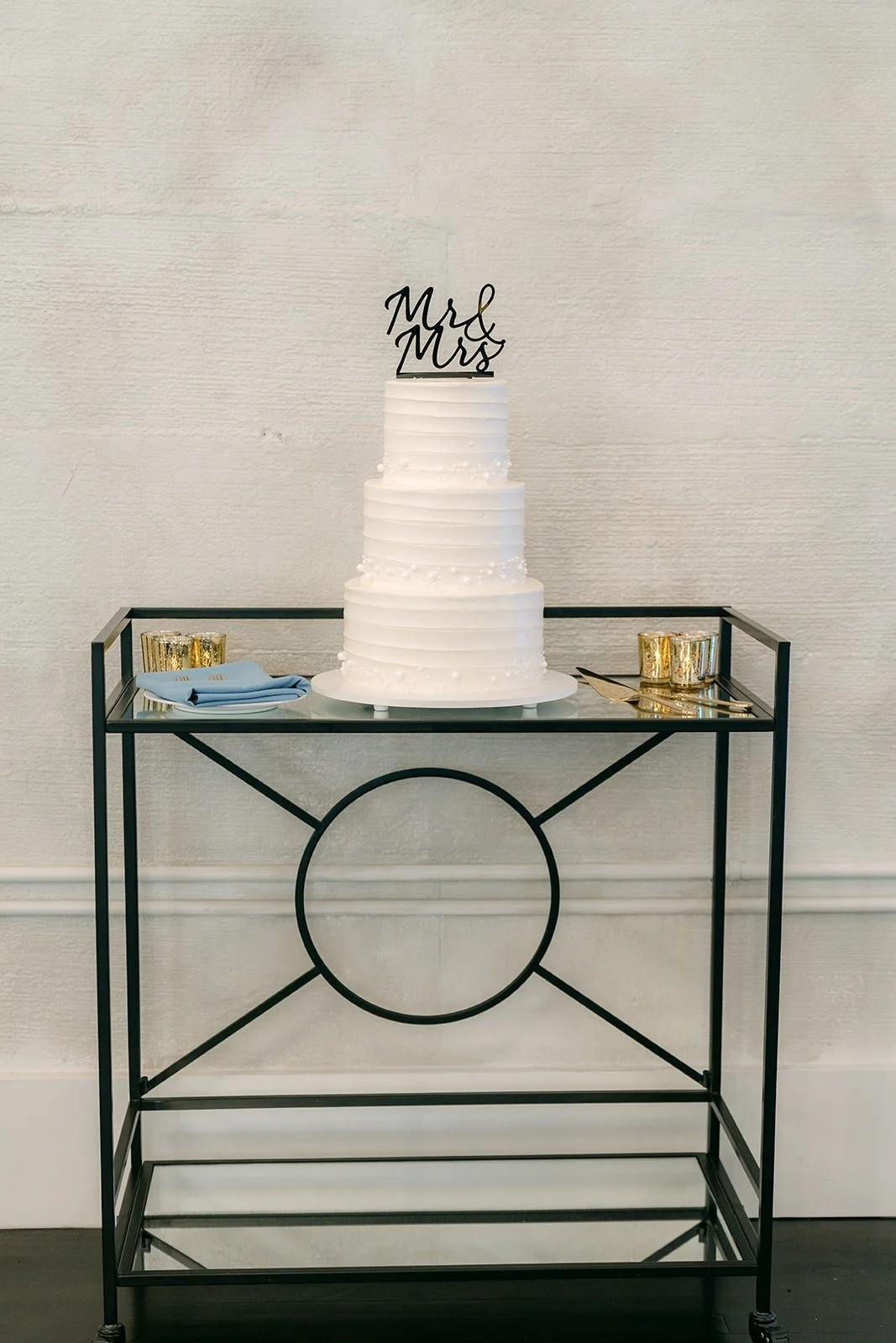 The white tiered cake on a gold bar cart
