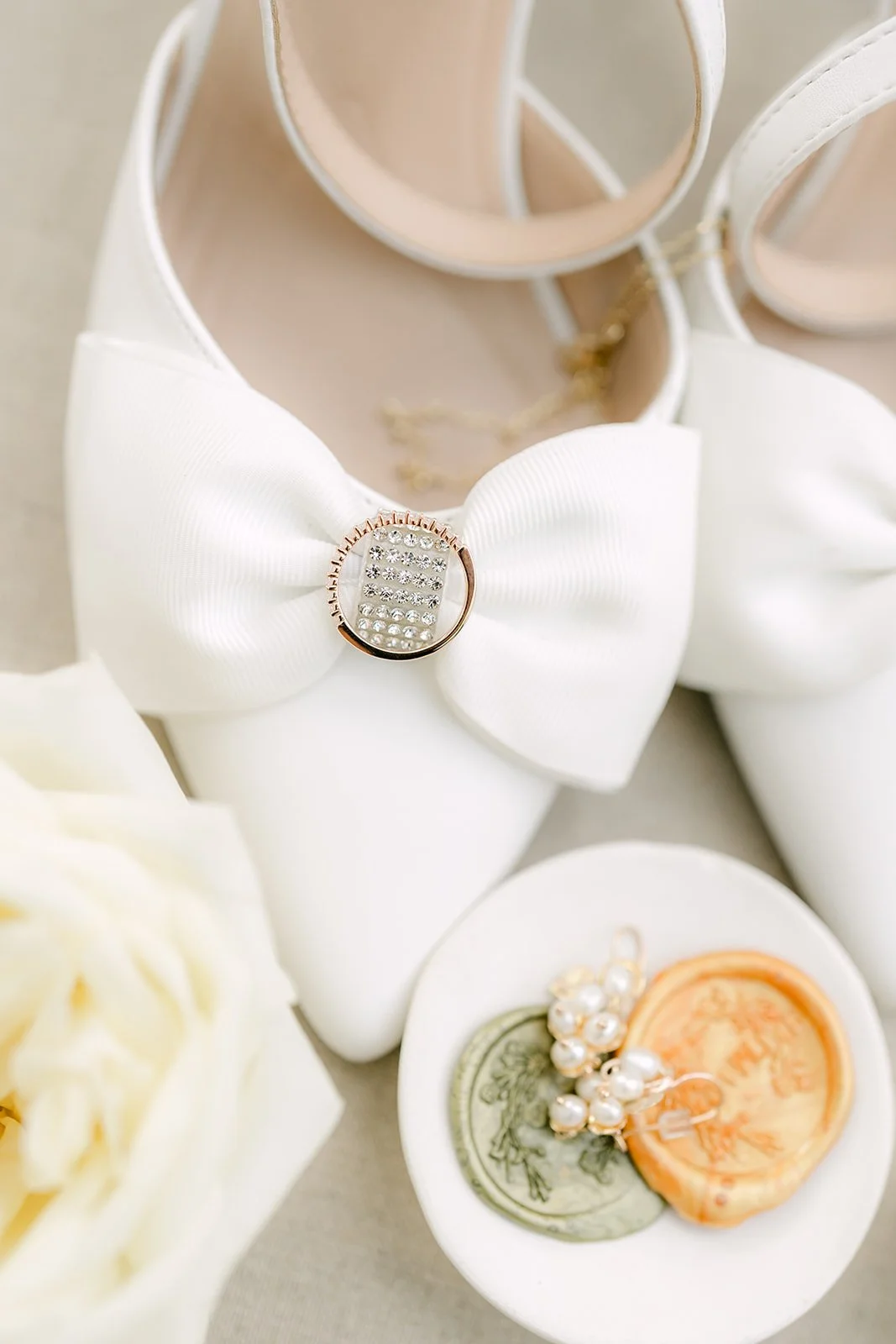 Mariana's white bow heels with pearl earrings and a gold wax seal