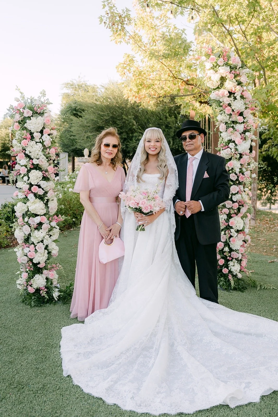 Konitha and Job with their wedding party beside the floral arch