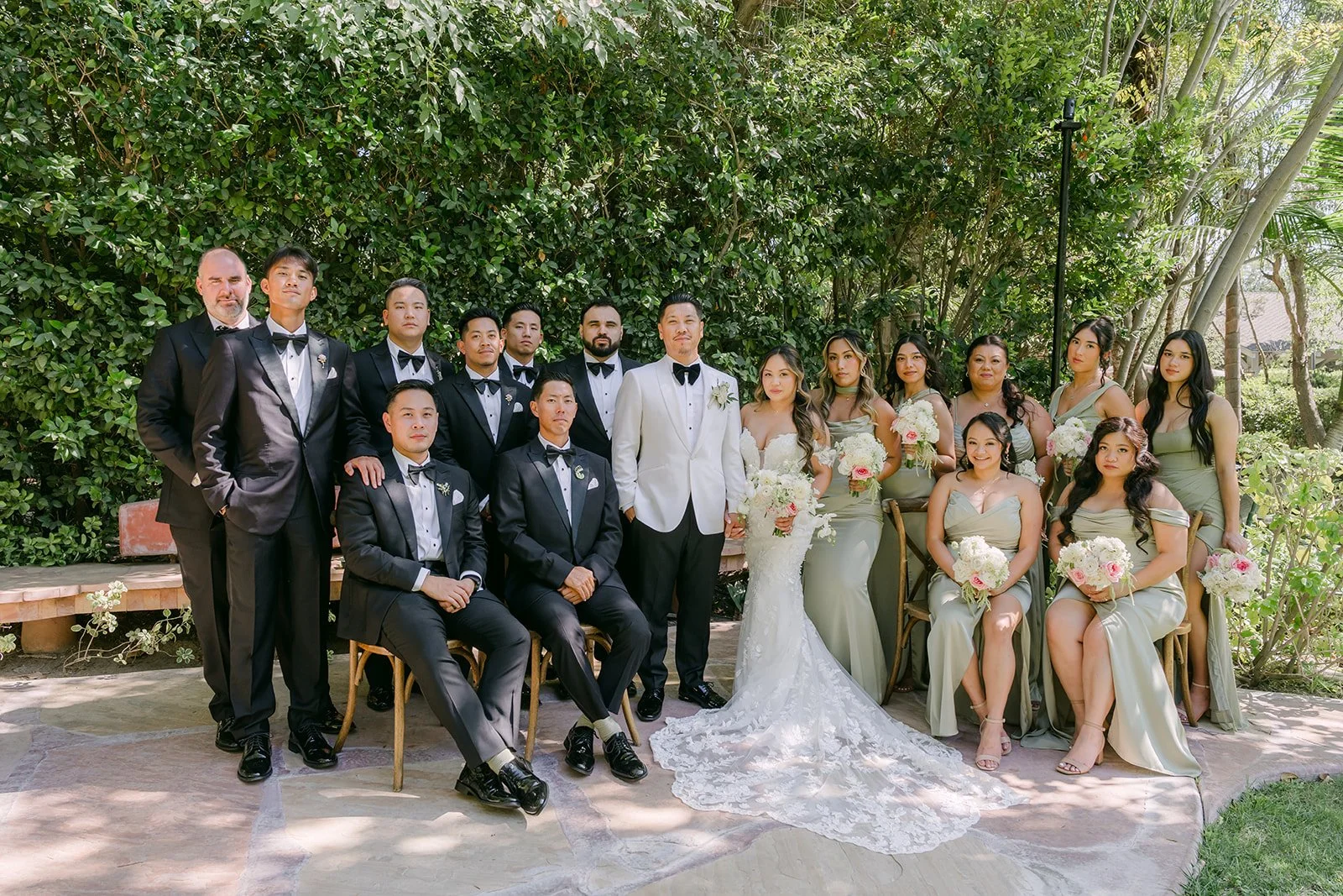 Nicole and Caryl with their full wedding party in black tuxedos and pistachio green gowns at Eden Gardens.