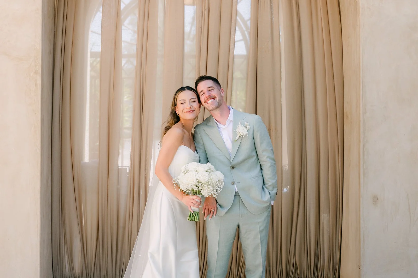 Kieu and Anthony smiling with her white rose bouquet