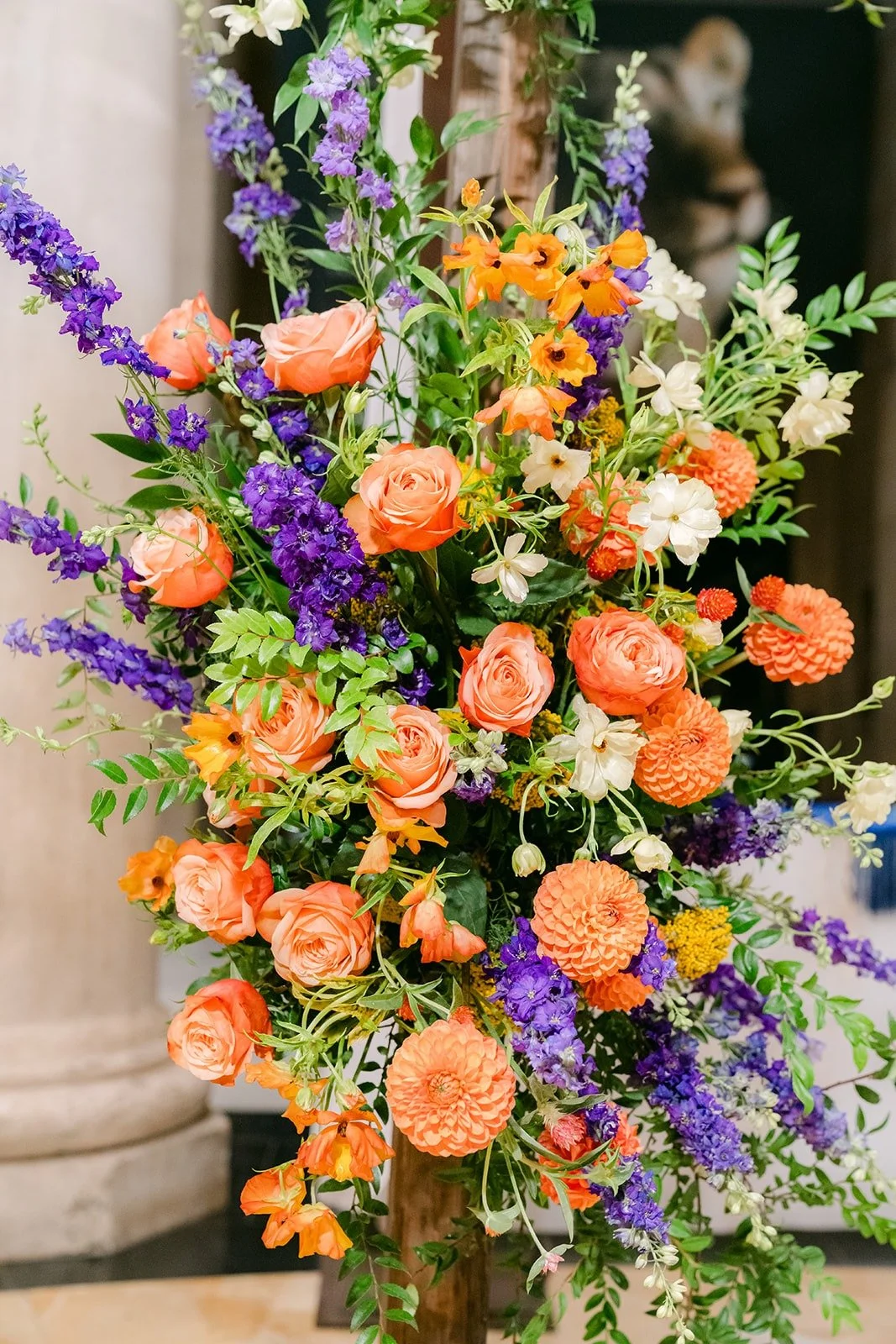 Peach roses, dahlias and violet stems on a floral column