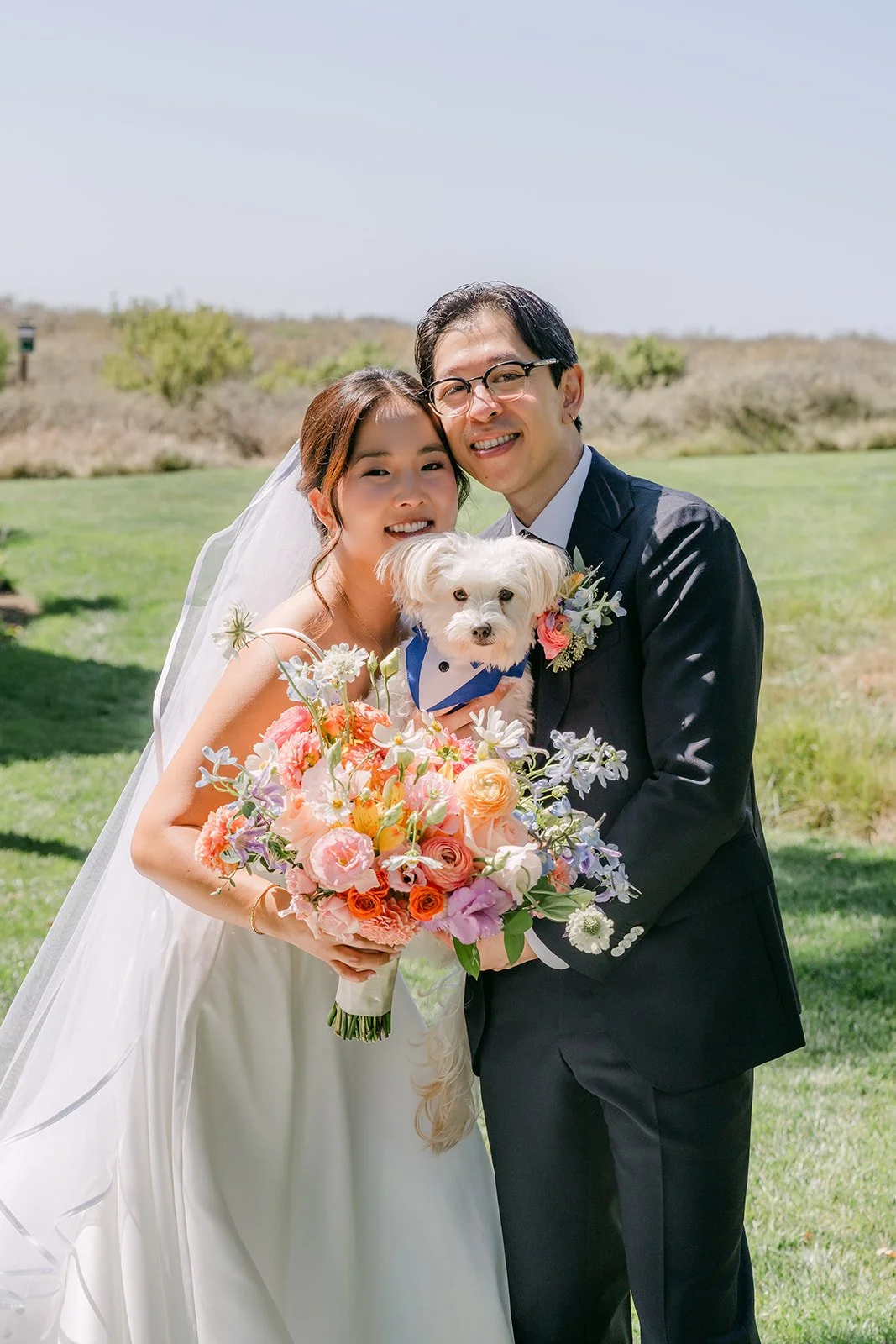 Saya and Leroy posing with bouquet and pup on the lawn
