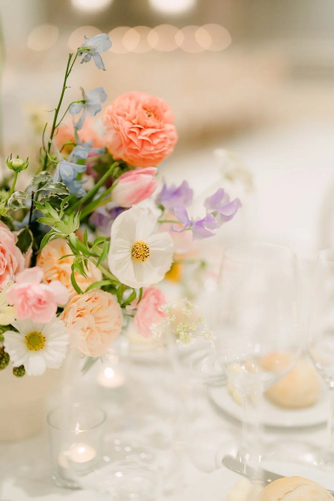 Peach and lavender blooms in a small vase at a guest table