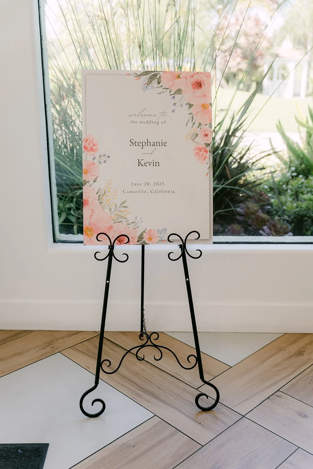 The welcome sign with pink and peach florals on a black easel