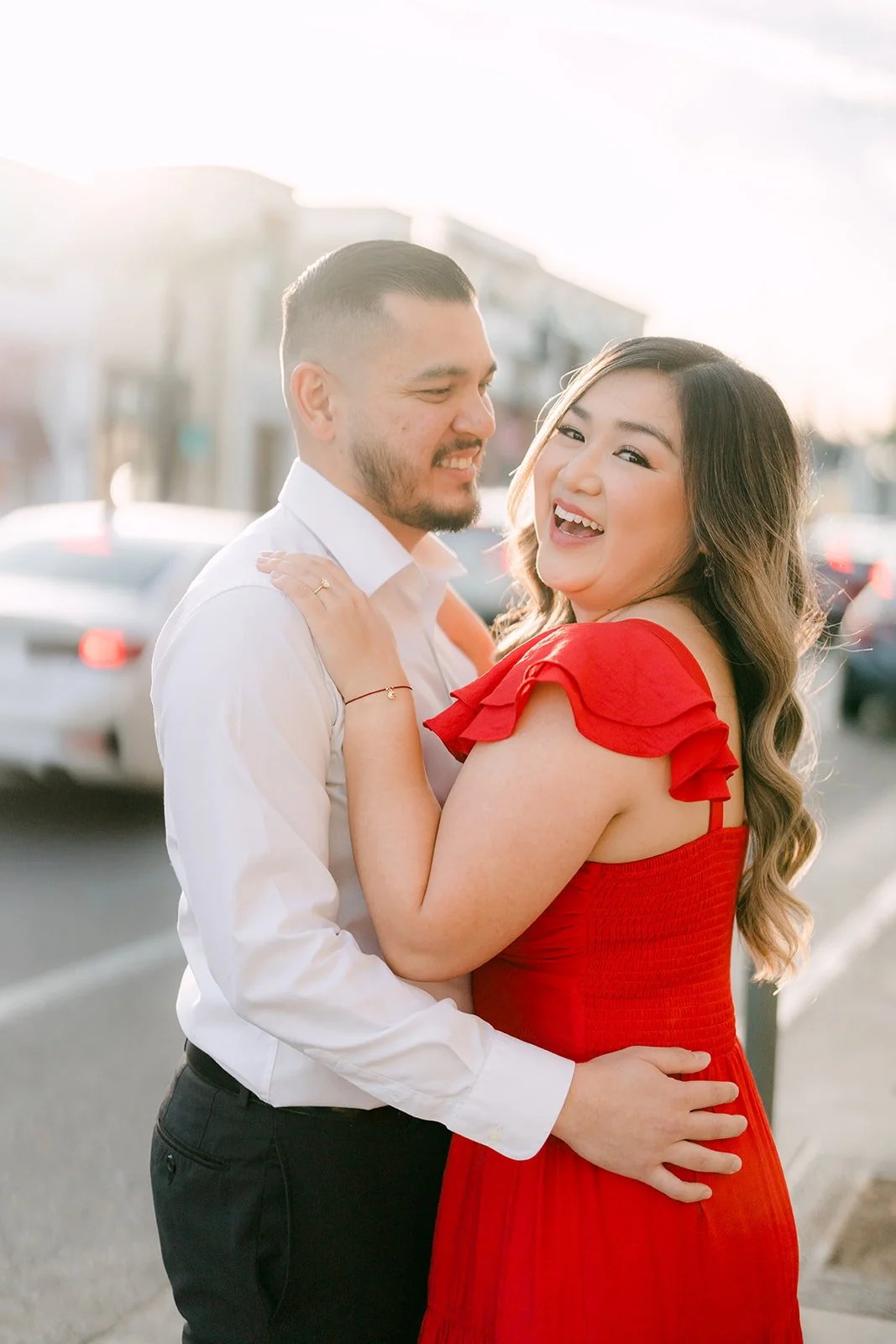Linh smiles over her shoulder while hugging Ankush on the street.