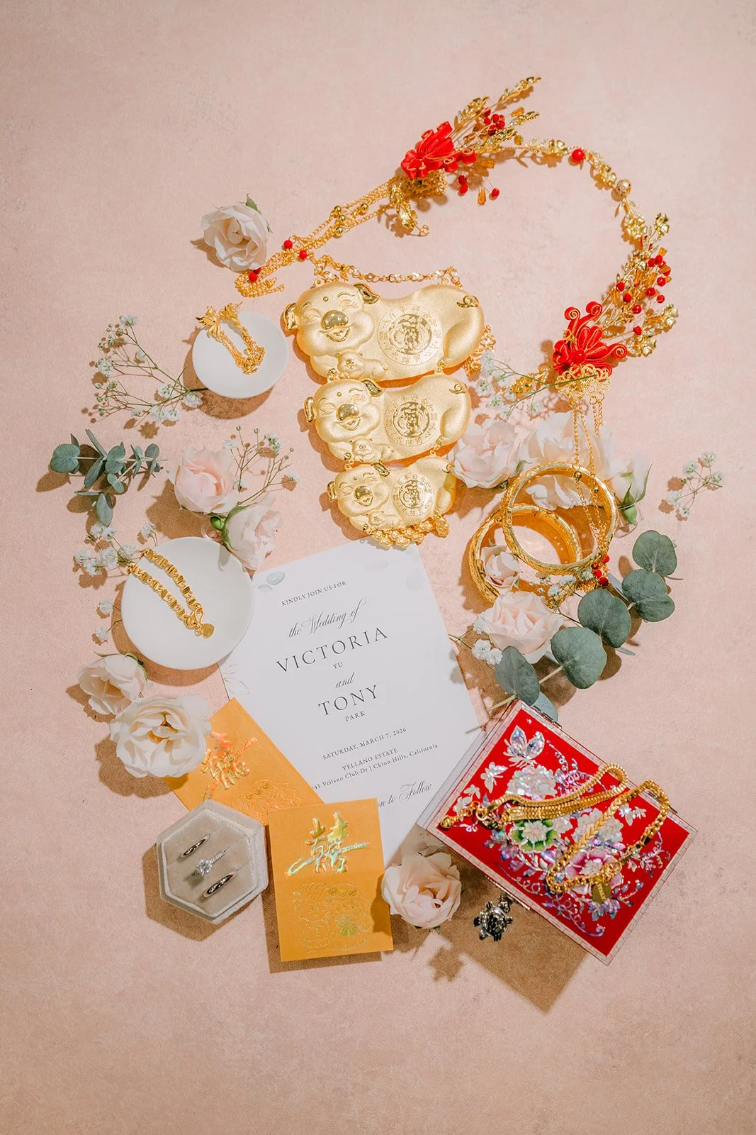 A flat lay of gold jewelry, red envelopes and invitations for the tea ceremony.