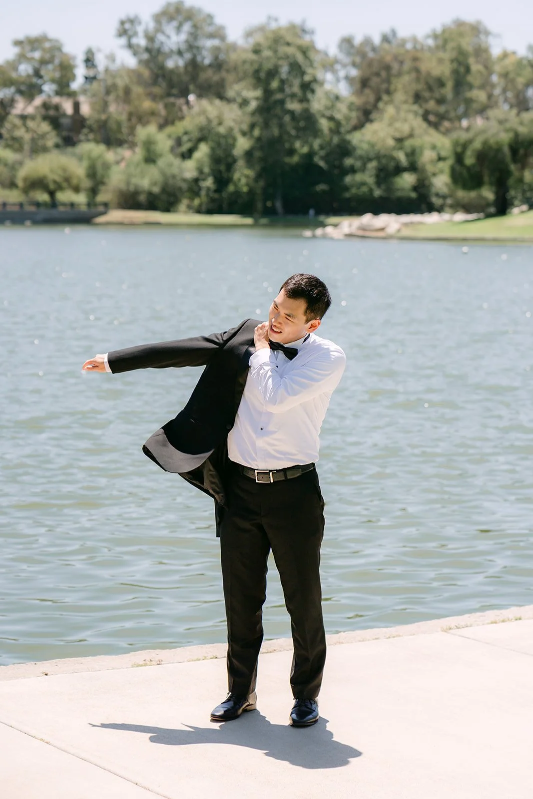 Austin putting on his tuxedo jacket by the lake