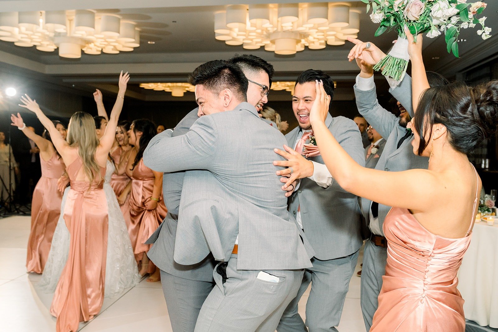 The wedding party dances in a circle around Betsy and Mikey
