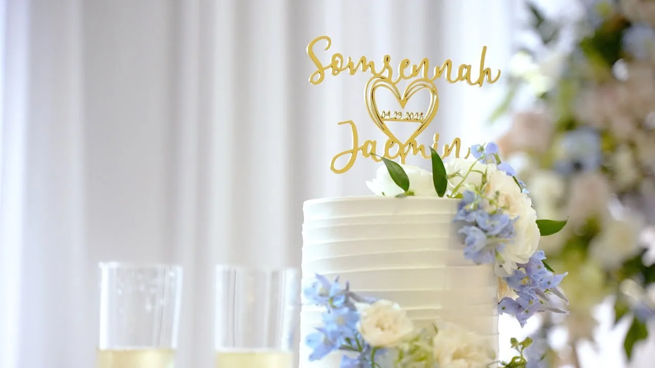 Video still of the two-tier wedding cake with a gold name topper