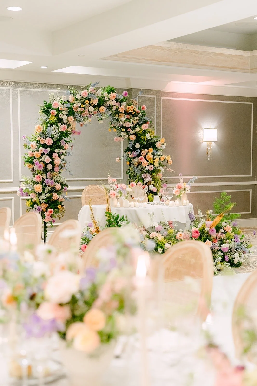 The sweetheart table in front of a round floral arch in the ballroom