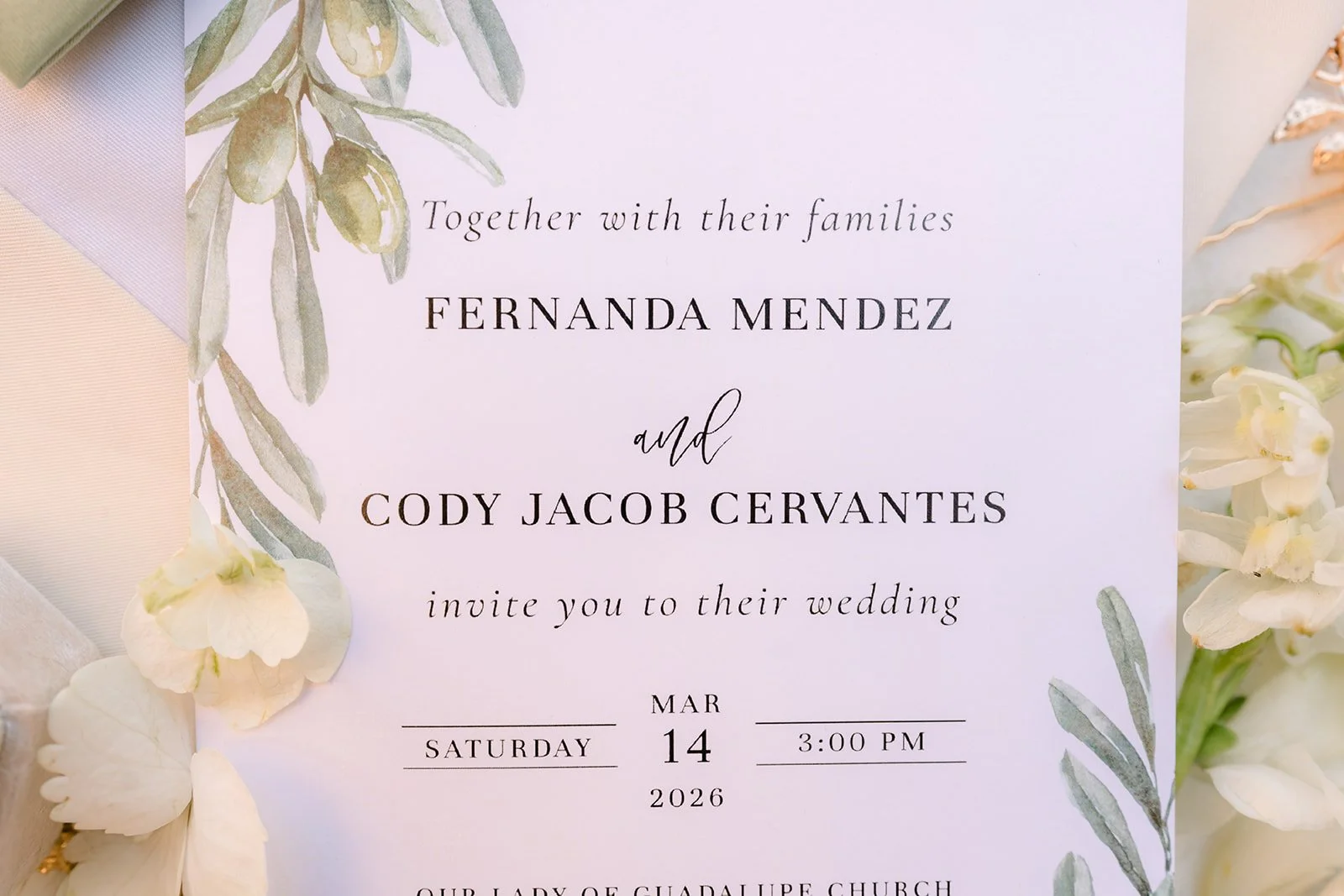 Fernanda and Cody's wedding invitation with greenery.