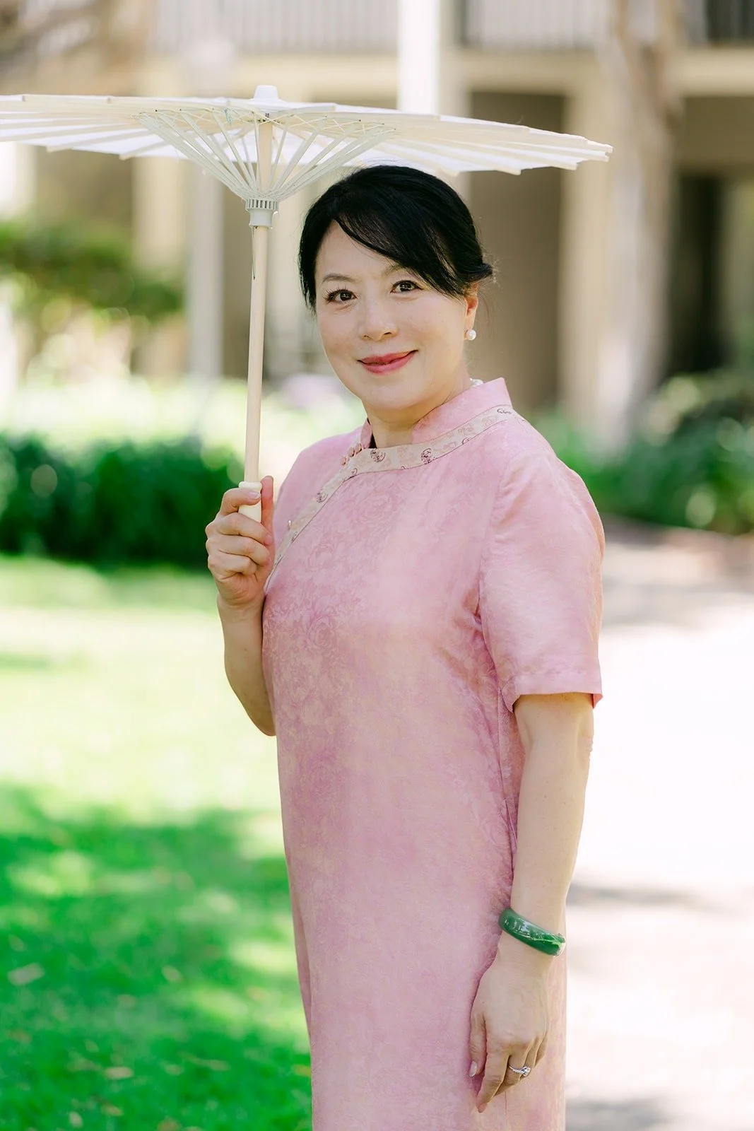 Tin's mom in a pink qipao holding a white parasol, photographed by One and Only Production