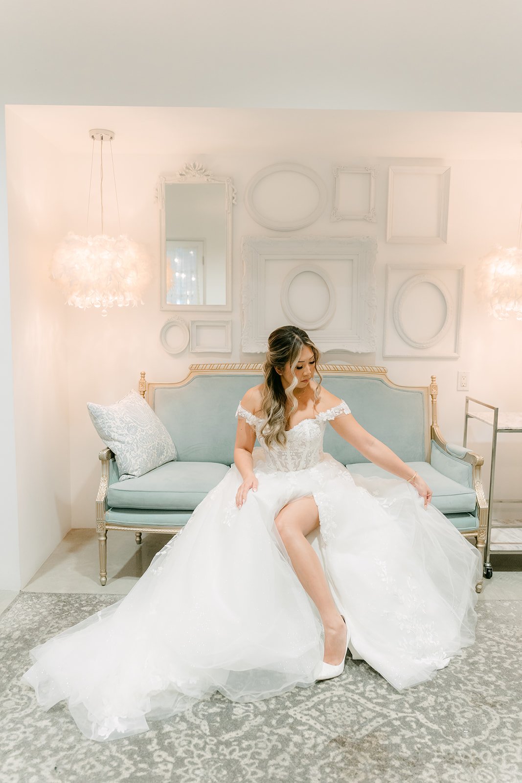 Raine putting on her heels on a blue velvet settee in the bridal suite