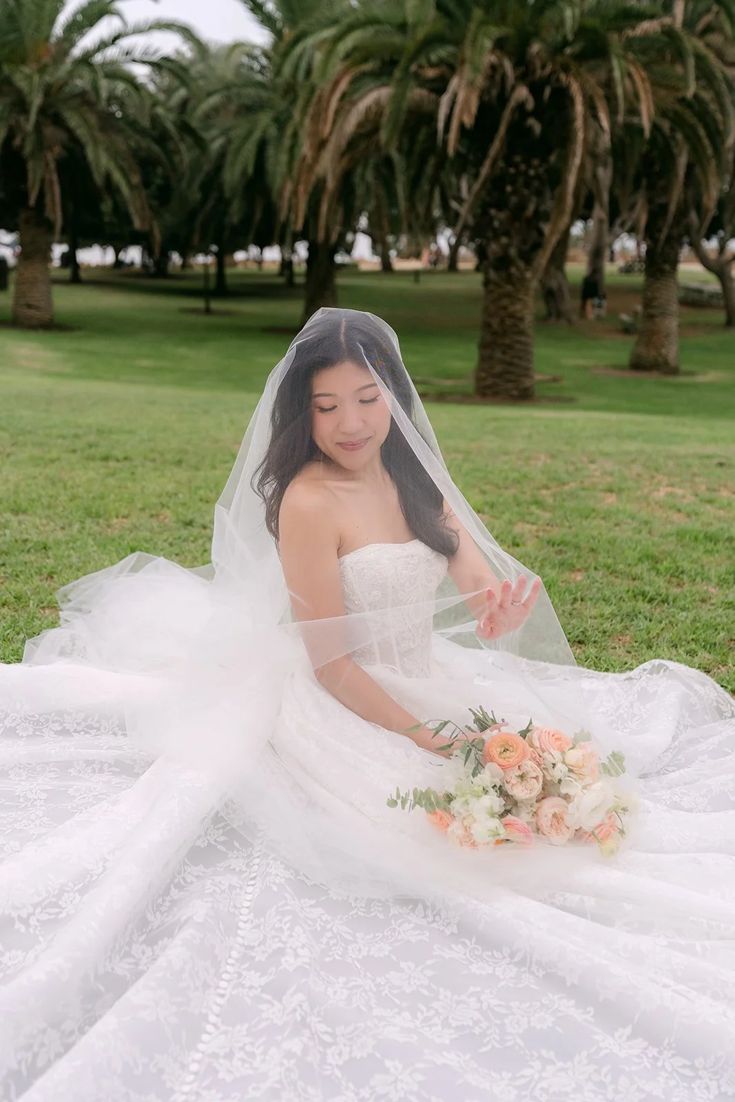 Kim seated on the lawn with her veil and train, photographed by One and Only Production