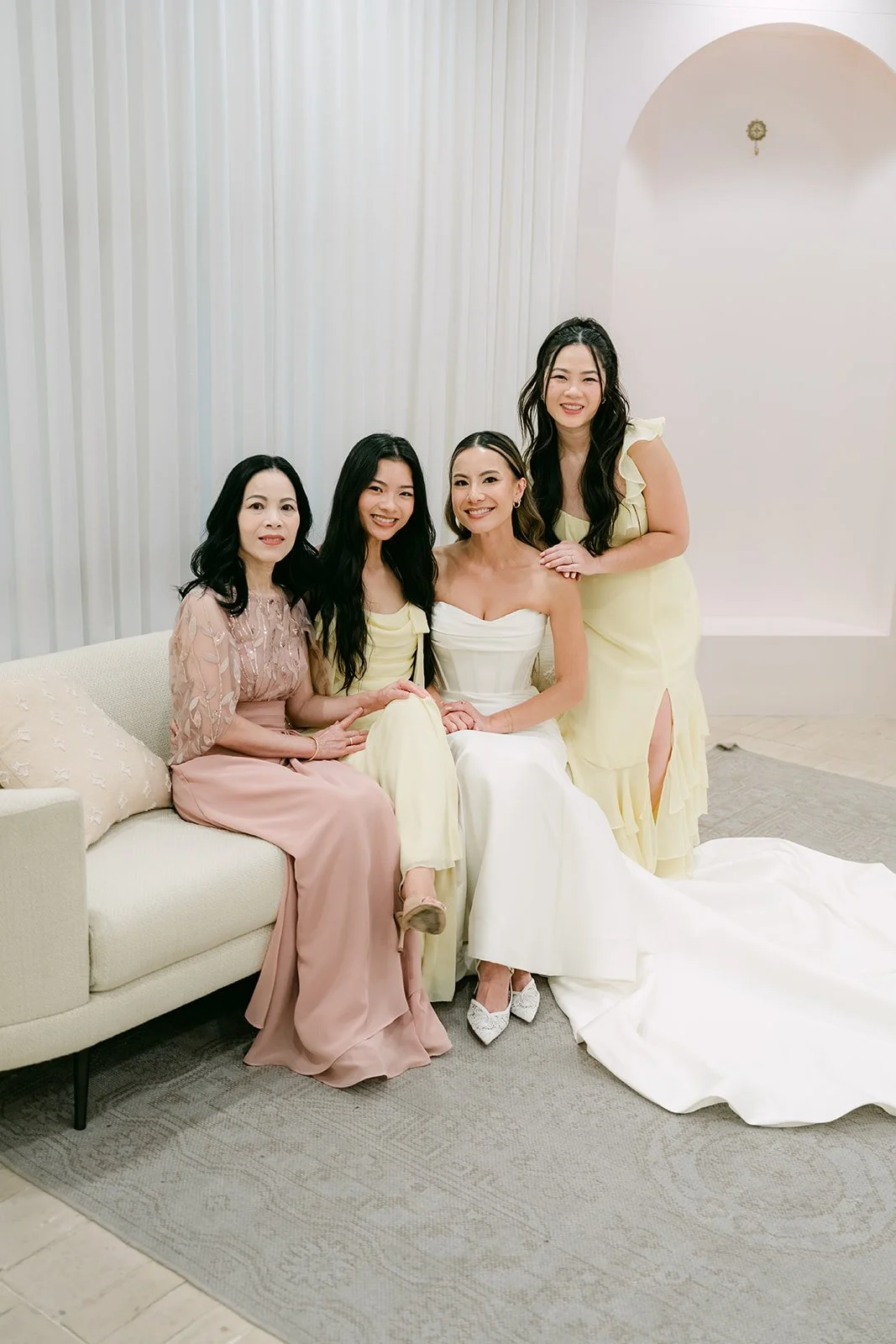 Bride sitting on the white sofa with her bridesmaids in the Serra Plaza bridal suite
