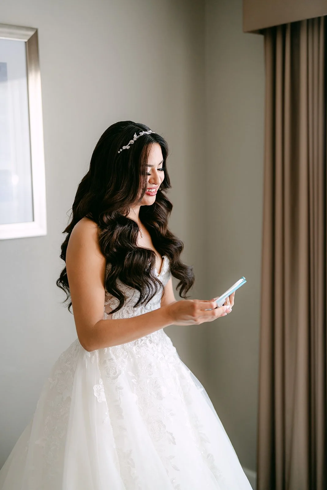 Sandra reading a letter by the window in her wedding gown.