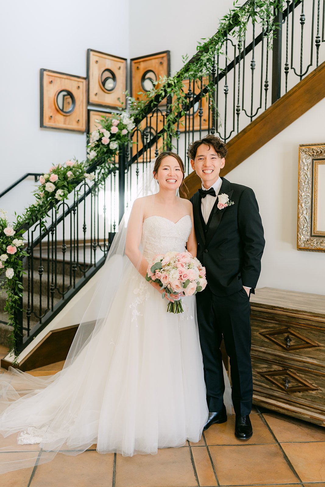 Victoria and Tony smiling together by the floral staircase