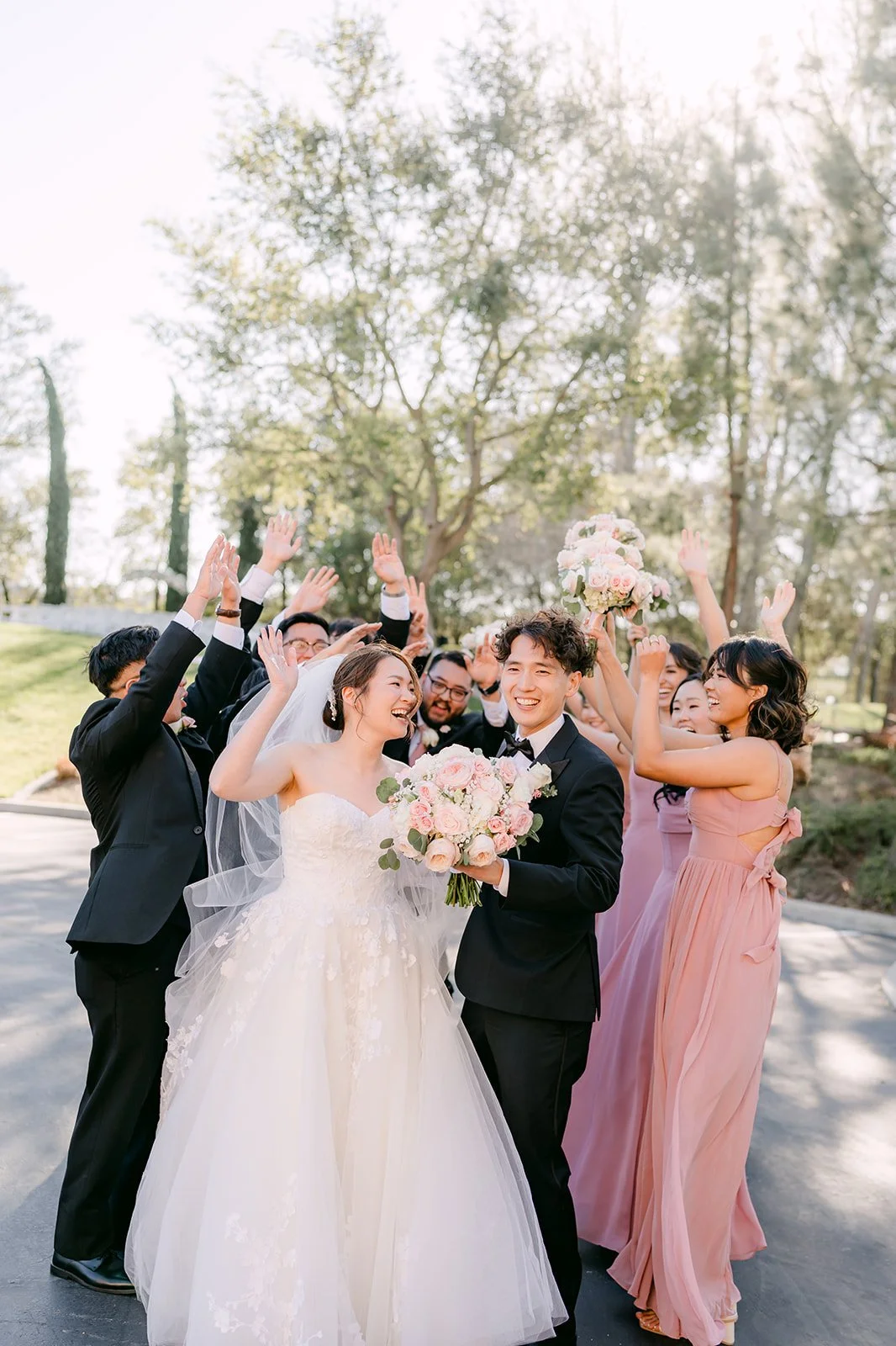 Wedding party throwing their arms up around Victoria and Tony